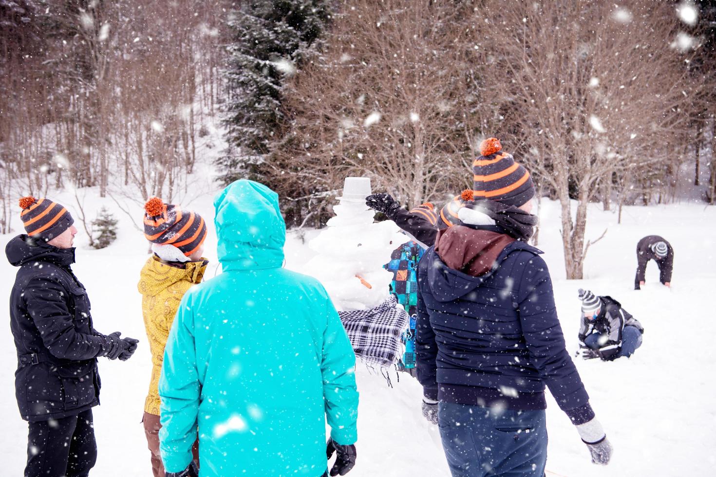 group of young people making a snowman photo