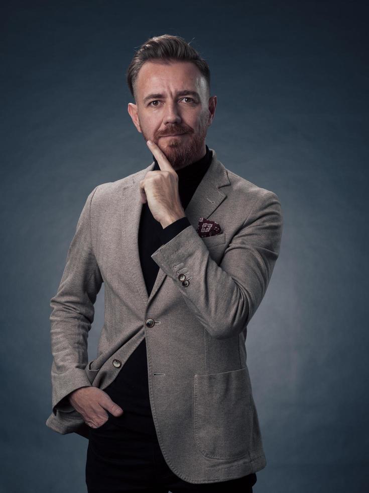 retrato de un elegante hombre de negocios de alto nivel con barba y ropa informal de negocios en un estudio fotográfico aislado en un fondo oscuro gesticulando con las manos foto