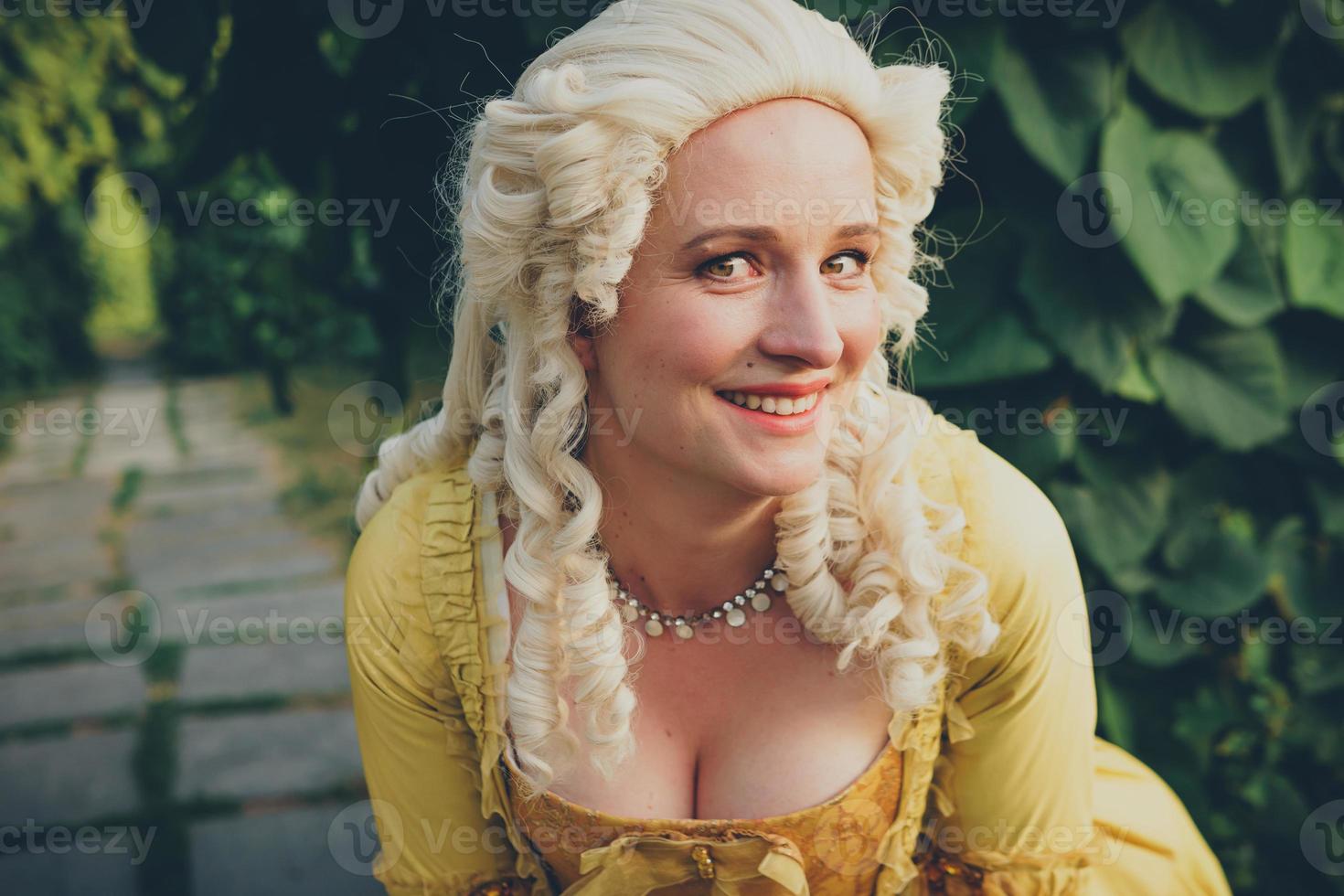 Portrait of blonde woman dressed in historical Baroque clothes with old fashion hairstyle, outdoors. photo