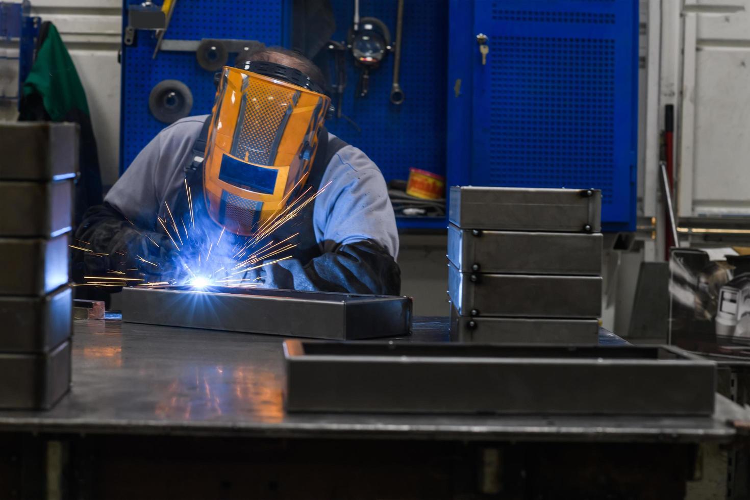 Professional welder performs work with metal parts in factory, sparks and electricity. Industry worker banner. photo