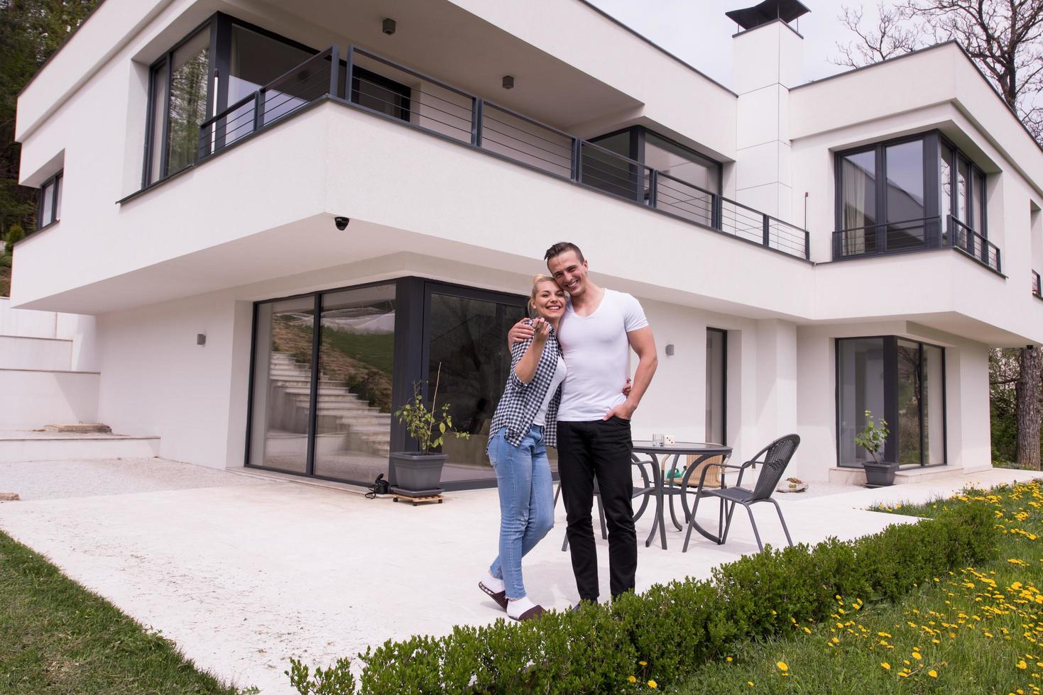 couple hugging in front of  new luxury home photo