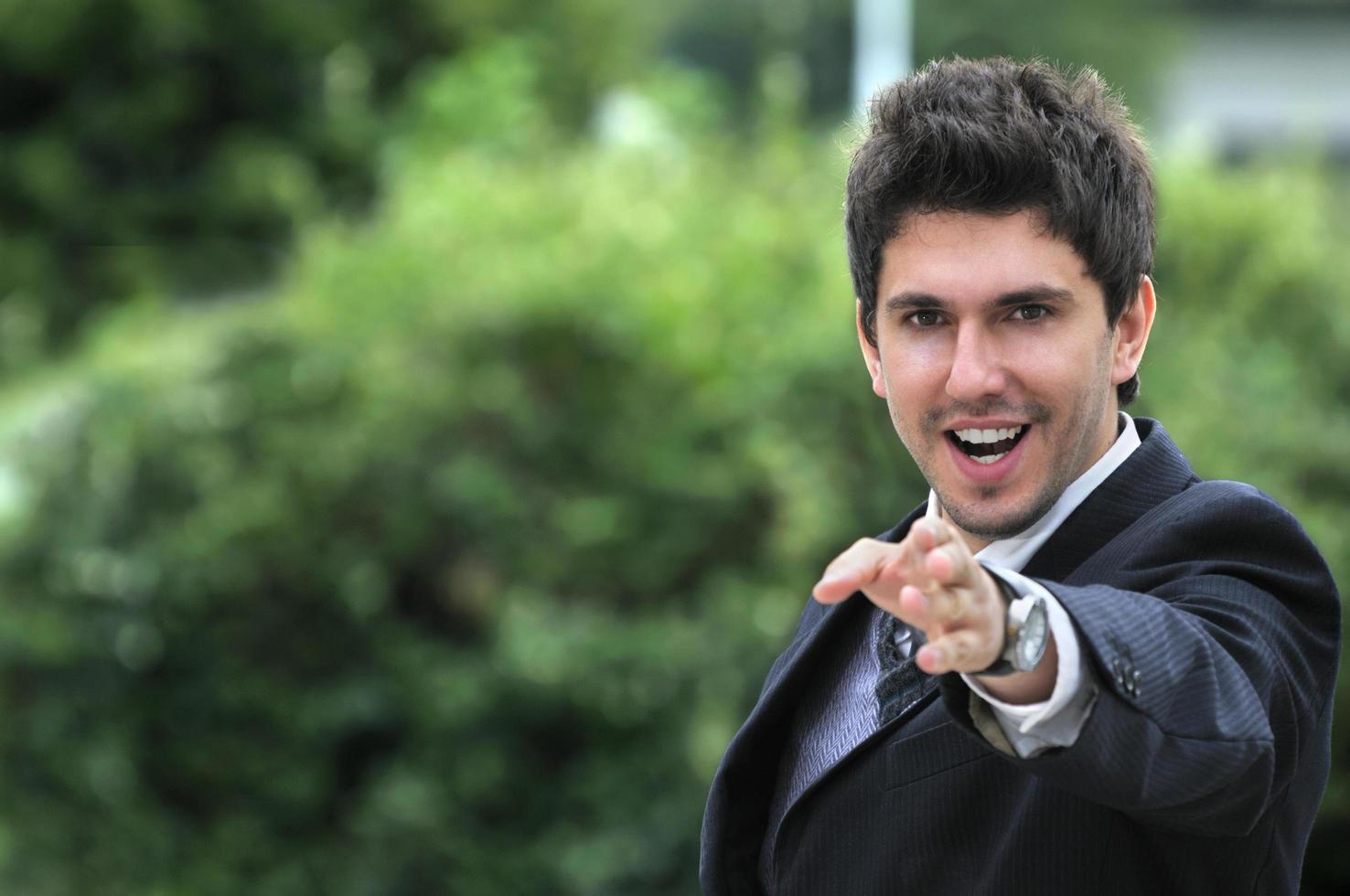 Young caucasian business man in a suite, pointing at camera to y photo