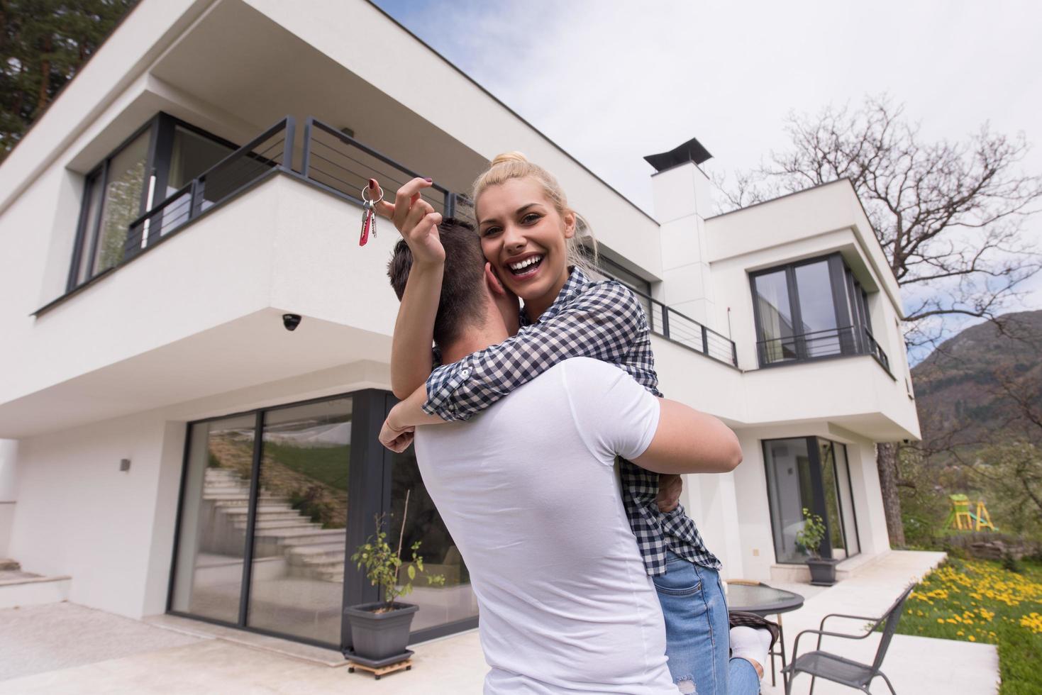 couple hugging in front of  new luxury home photo