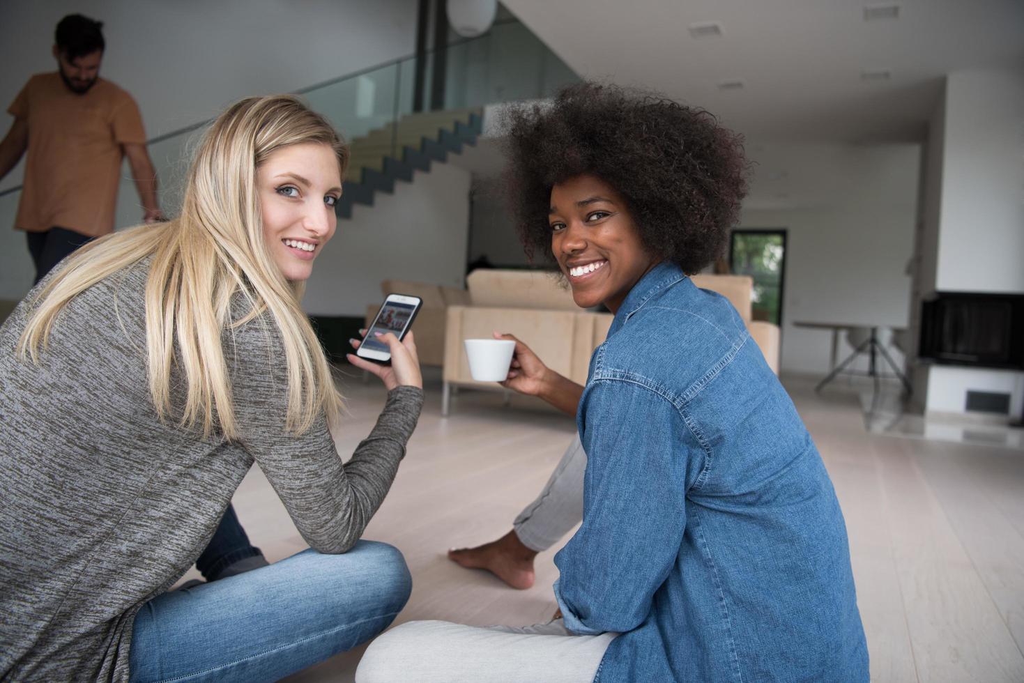 young multiethnic women sit on the floor and drinking coffee photo