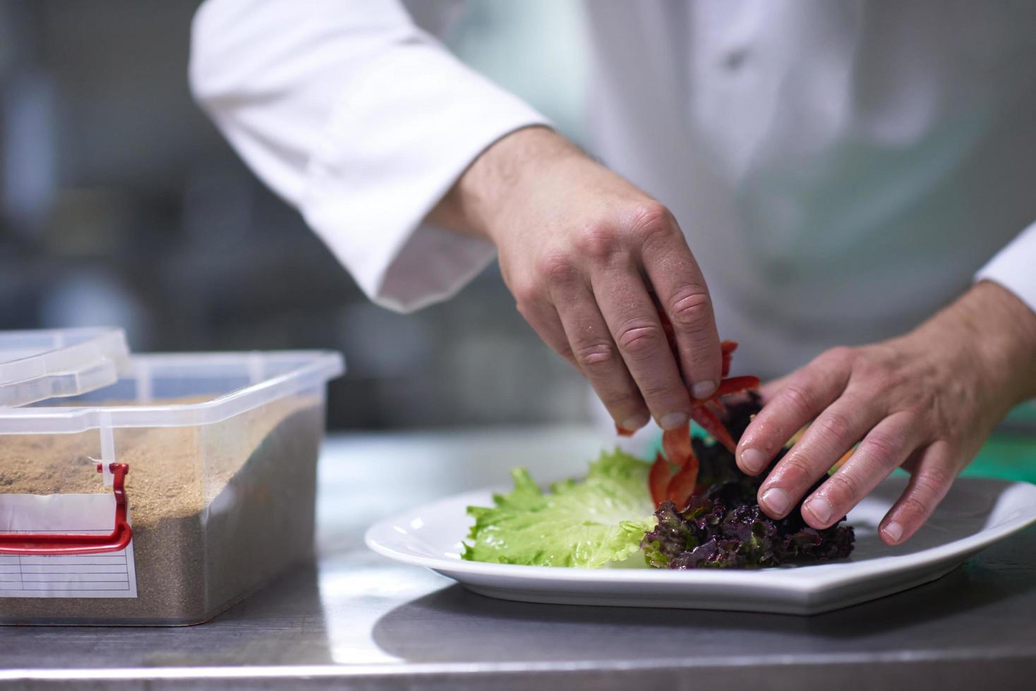 chef in hotel kitchen preparing and decorating food photo