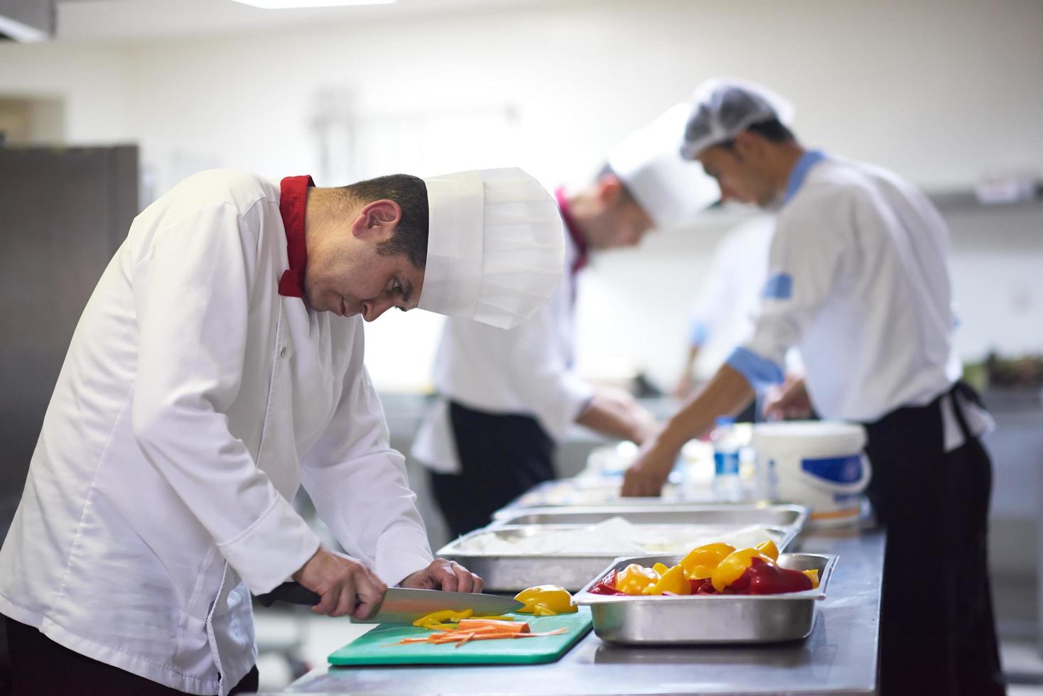 chef in hotel kitchen  slice  vegetables with knife photo