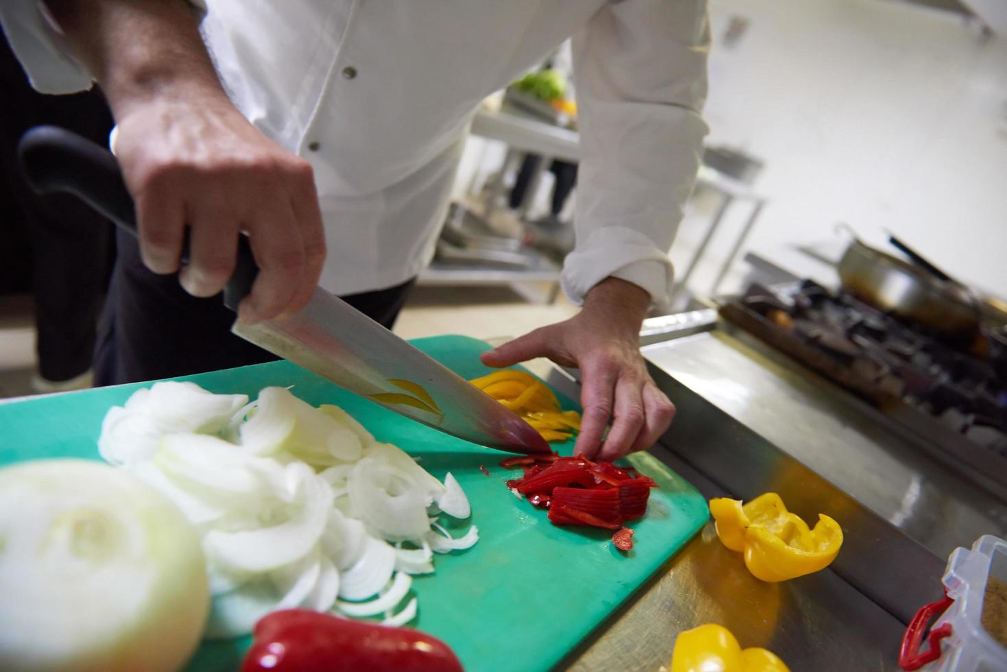 chef in hotel kitchen  slice  vegetables with knife photo