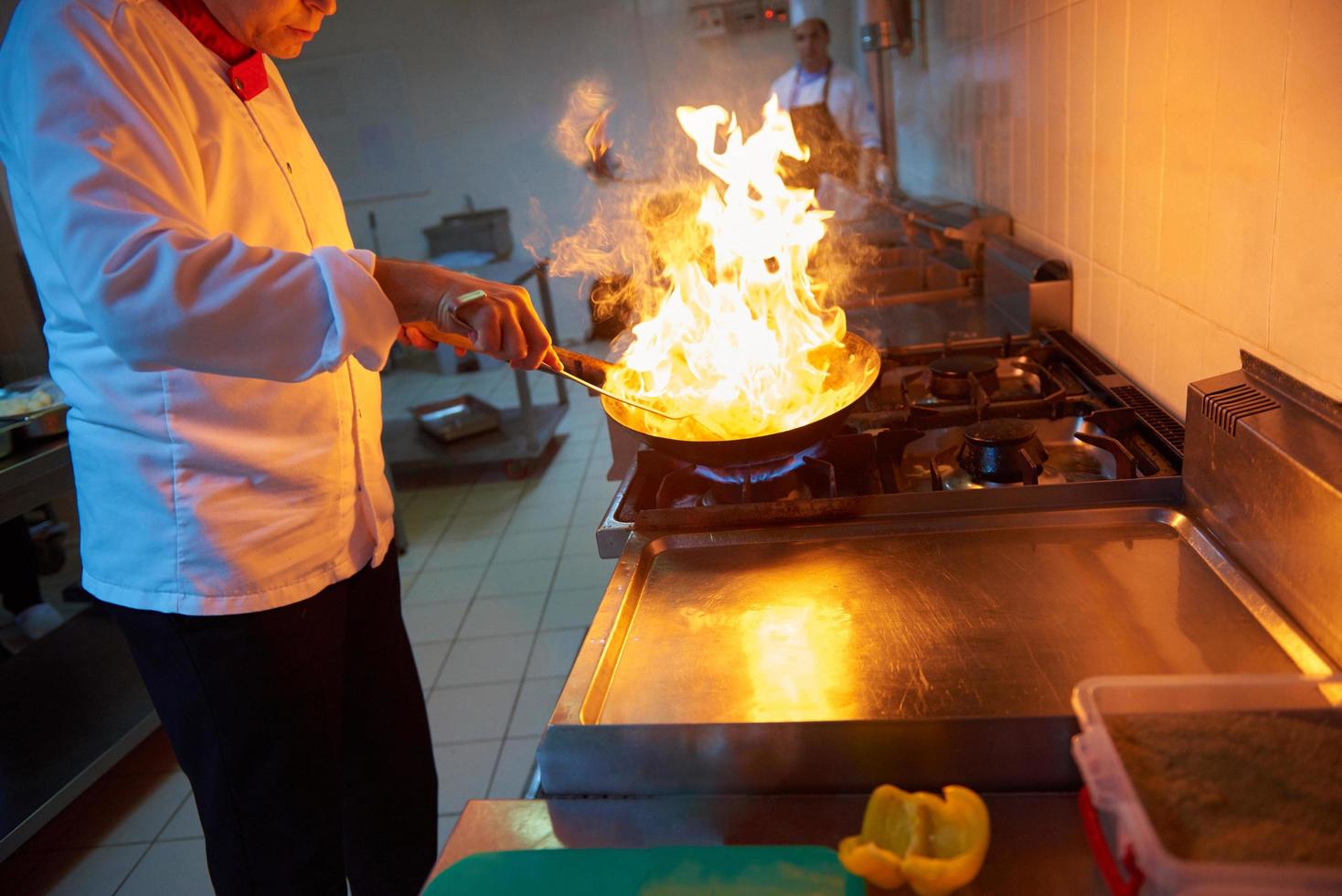 chef en la cocina del hotel prepara comida con fuego foto