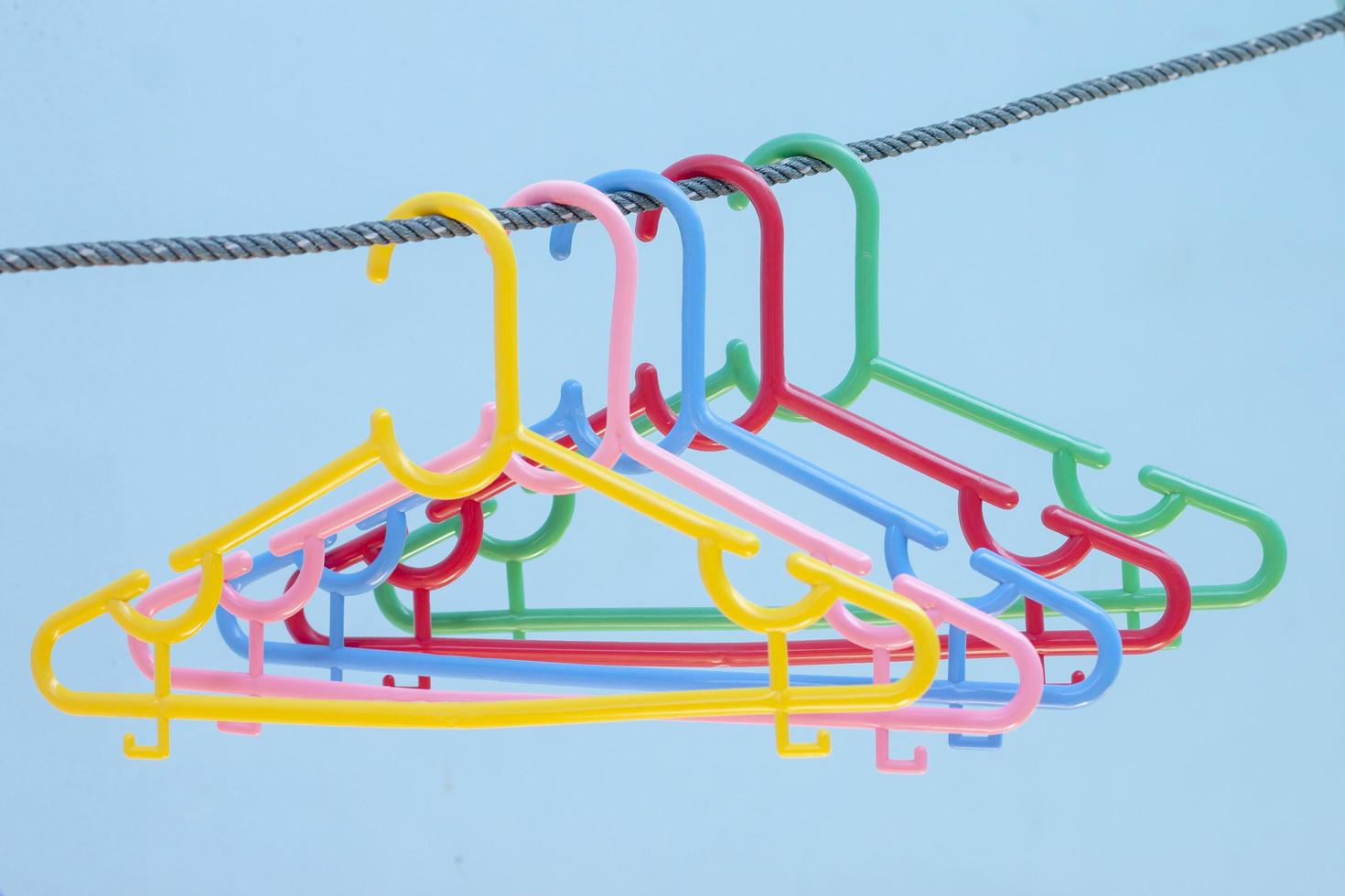 Colorful plastic hangers on the rope on blue cement wall blur background. photo