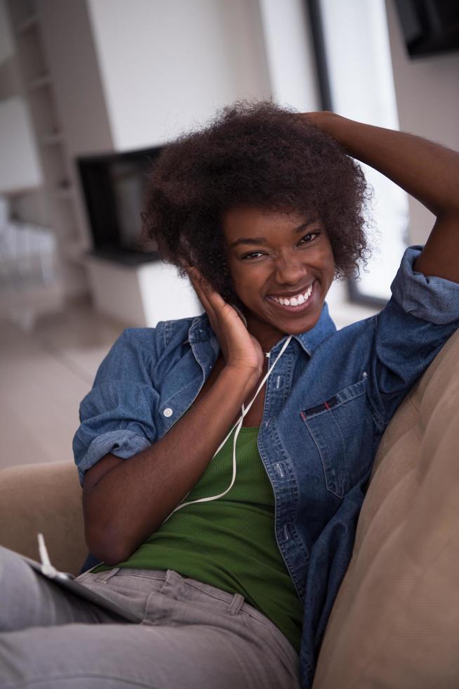 African american woman at home in chair with tablet and head phones photo