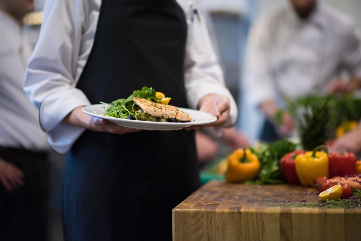 Chef hands holding dish of fried Salmon fish fillet photo