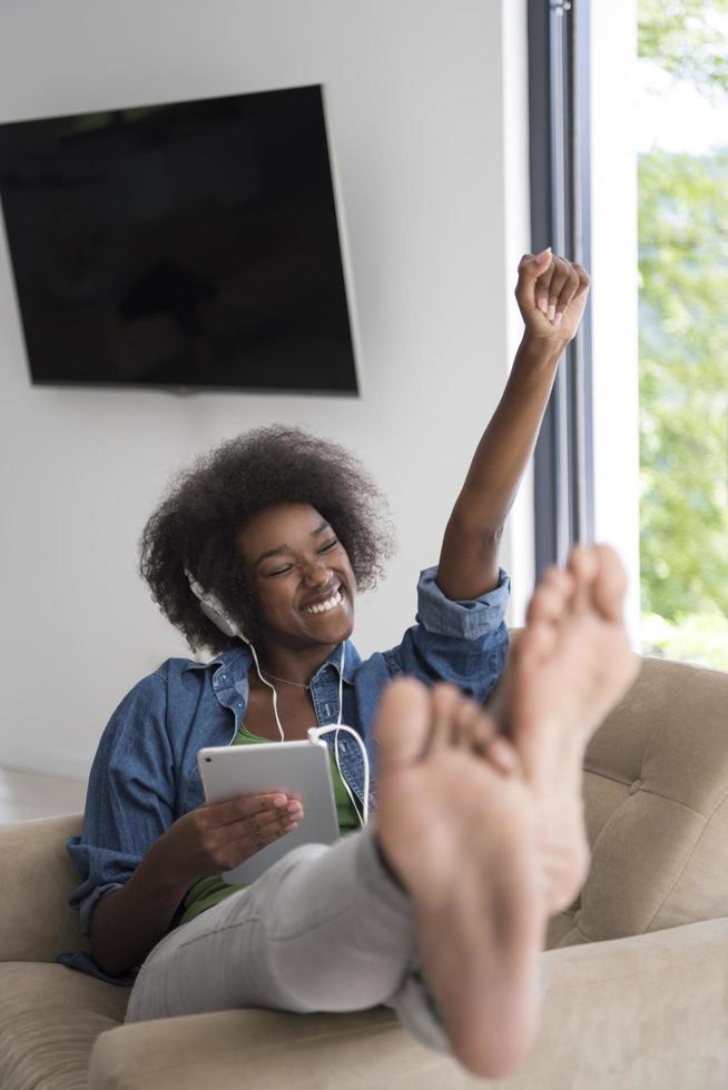African american woman at home in chair with tablet and head phones photo