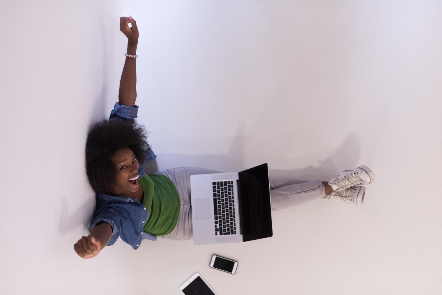 mujer afroamericana sentada en el suelo con vista superior del portátil foto