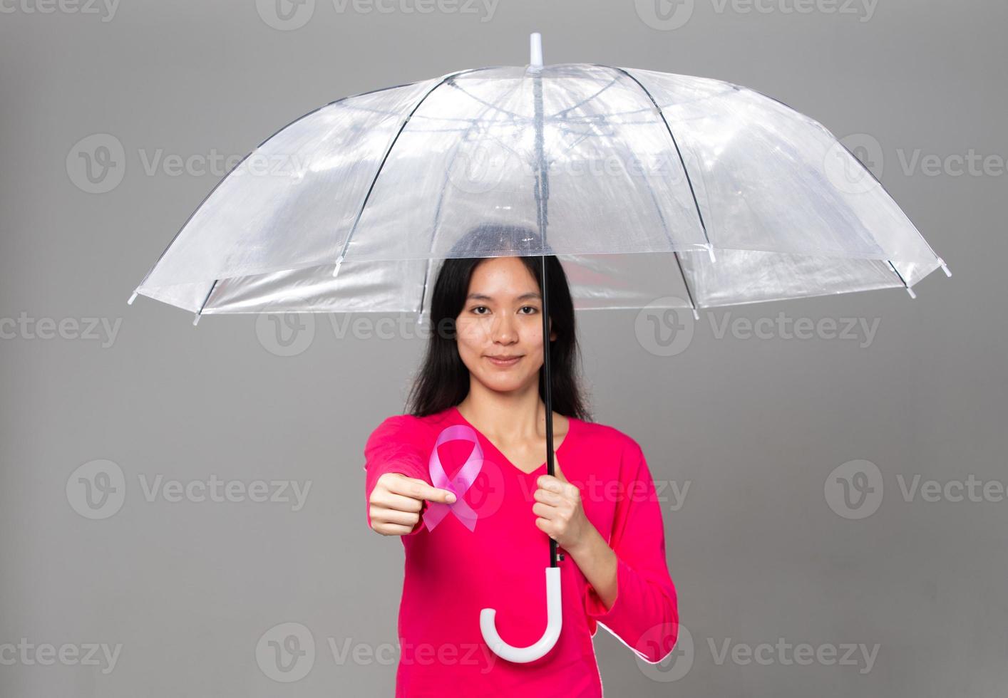 octubre mes de concientización sobre el cáncer de mama, mujer adulta con vestido rosa mano sosteniendo cinta rosa y paraguas para apoyar la protección. espacio de copia del concepto del día internacional de la mujer, la madre y el día mundial del cáncer foto