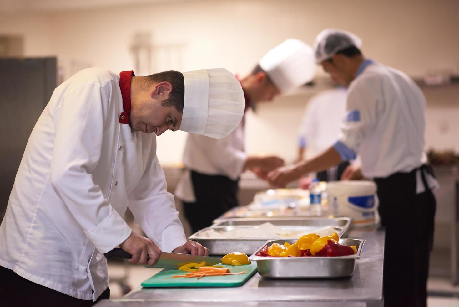 chef en la cocina del hotel cortar verduras con cuchillo foto