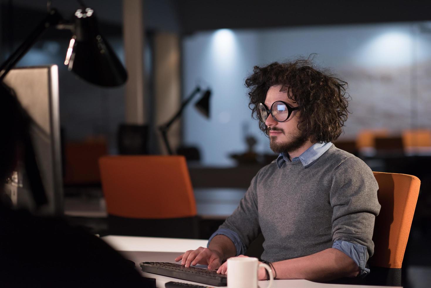 hombre trabajando en una computadora en una oficina de inicio oscura foto