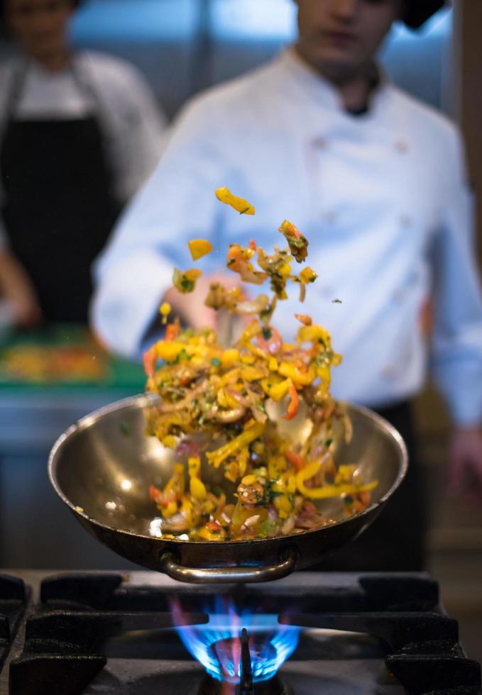 chef volteando verduras en wok foto