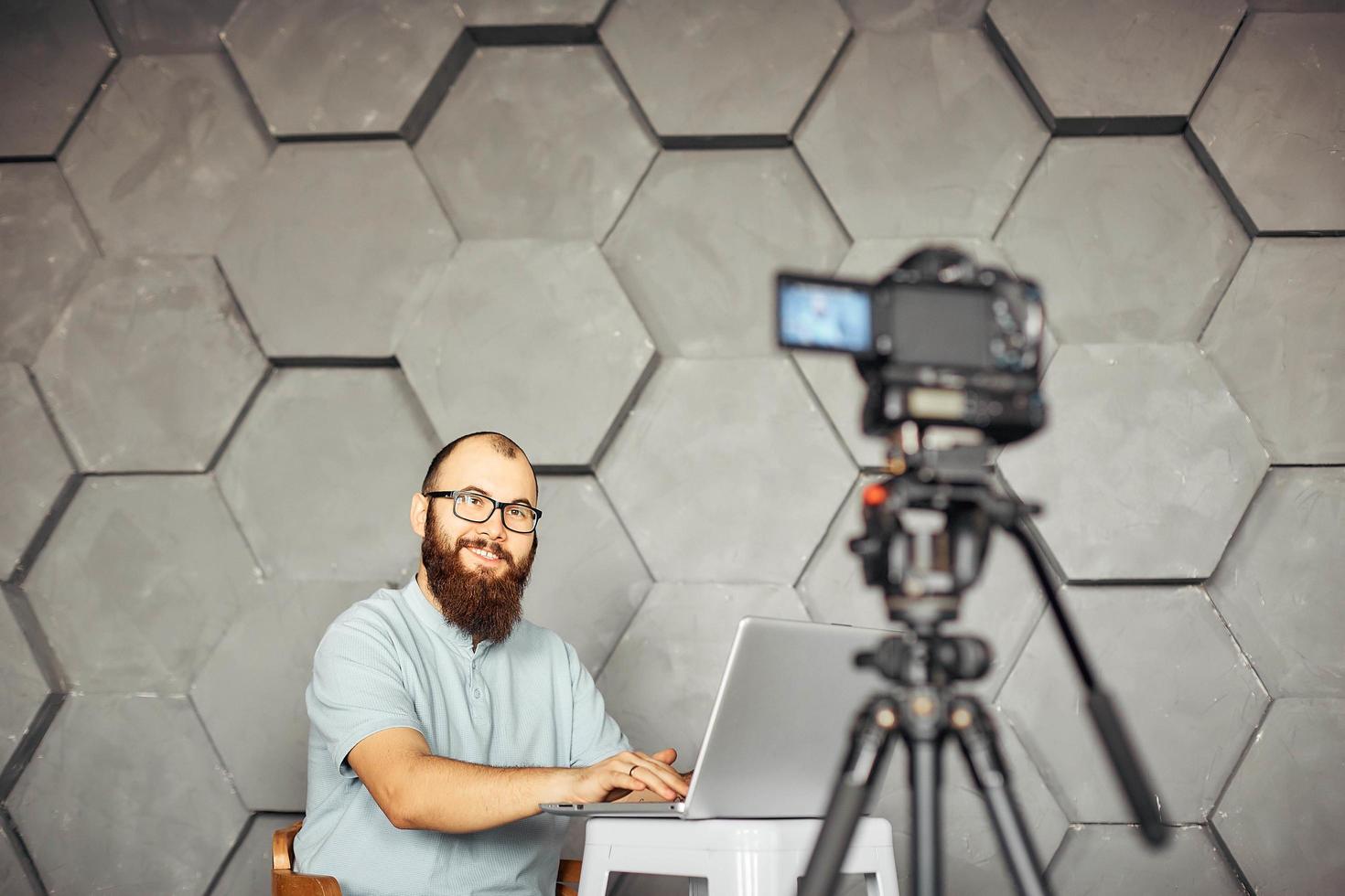 content creation for social media. bearded man shooting video of himself using camera on tripod. modern technology and blogging freelance work concept. photo