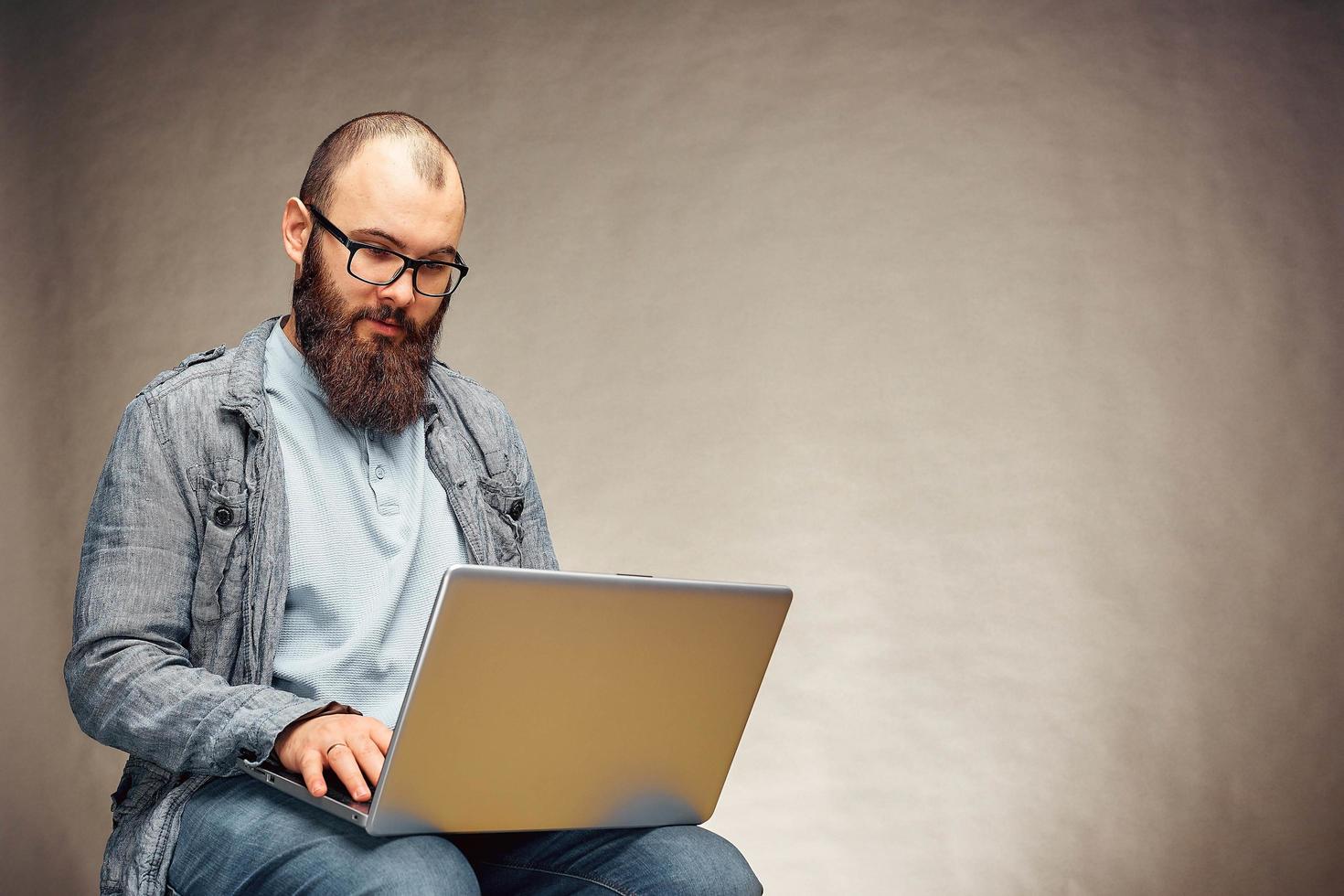 estilo de vida exitoso hombre independiente con barba logra un nuevo objetivo con una computadora portátil en el interior del loft. foto