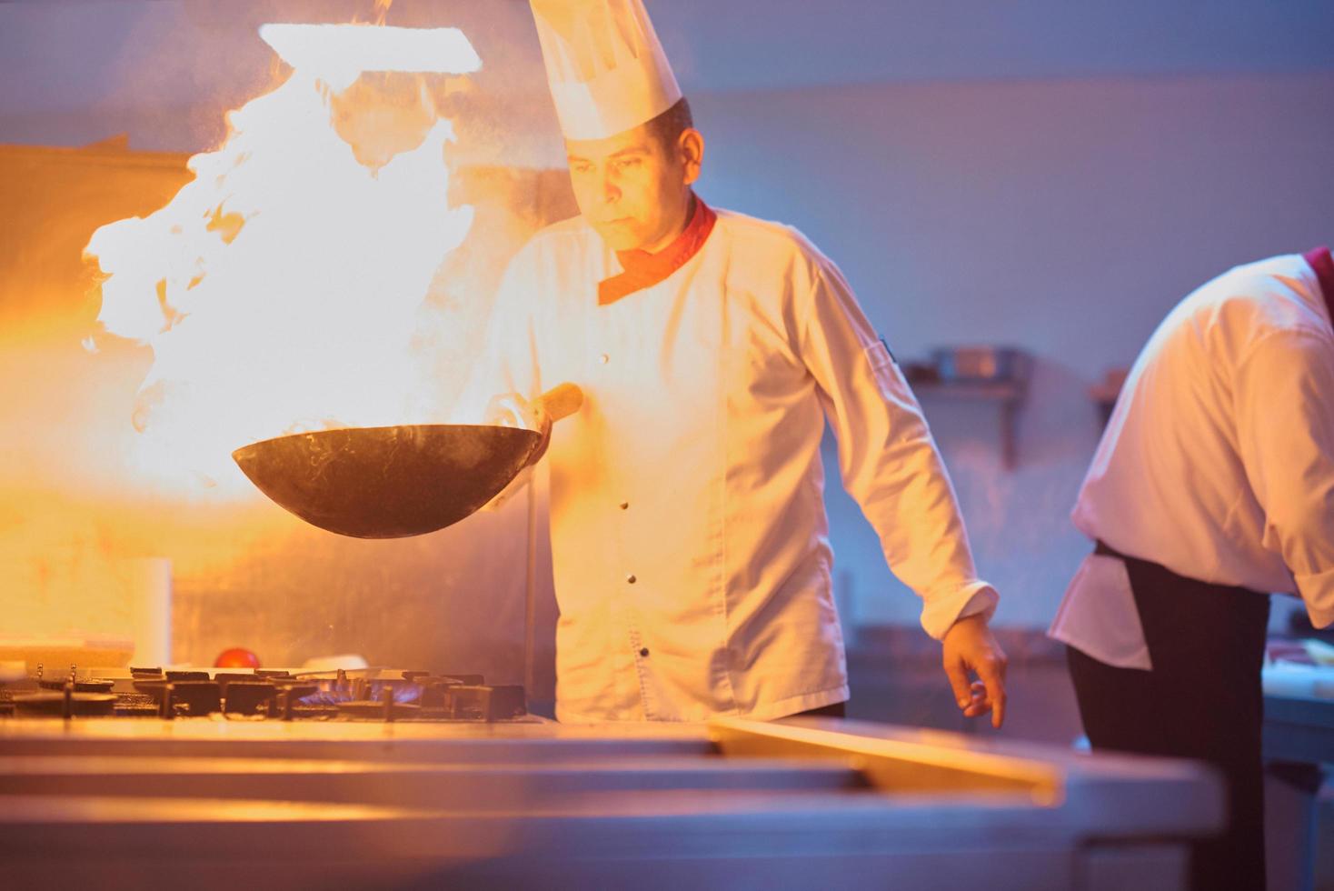 chef in hotel kitchen prepare food with fire photo