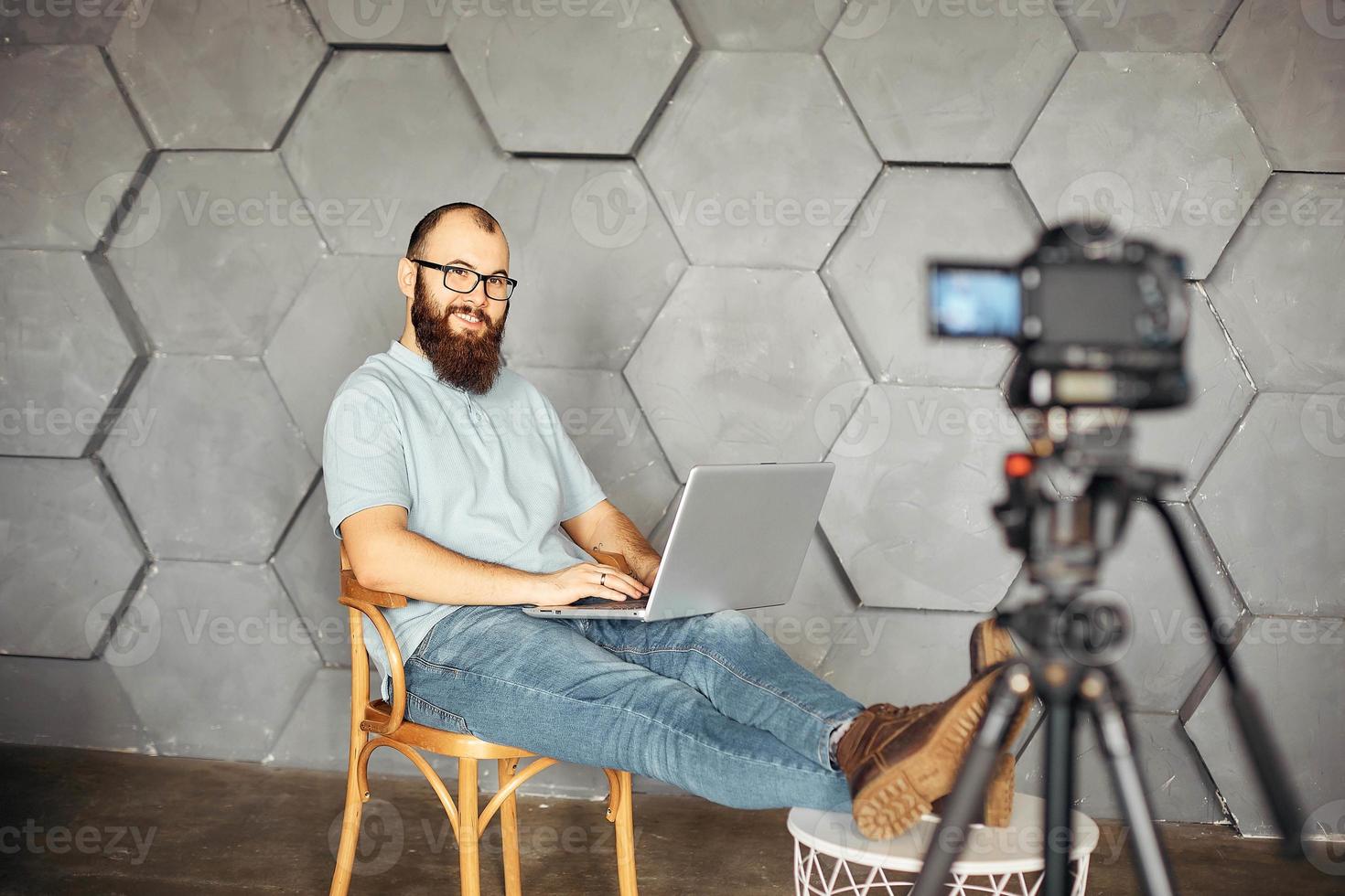 content creation for social media. bearded man shooting video of himself using camera on tripod. modern technology and blogging freelance work concept. photo