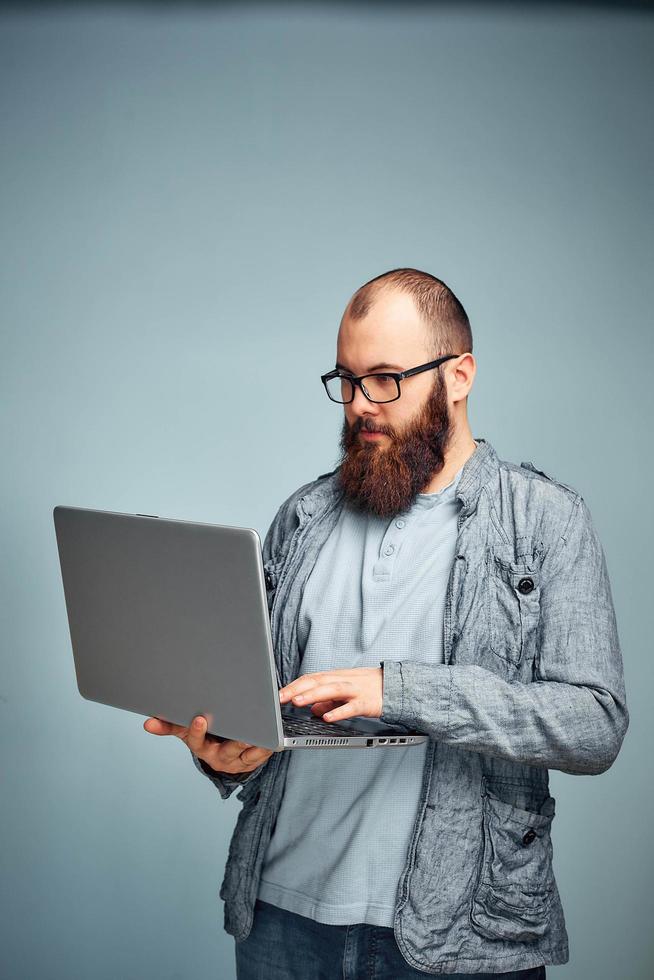 estilo de vida exitoso hombre independiente con barba logra un nuevo objetivo con una computadora portátil en el interior del loft. foto