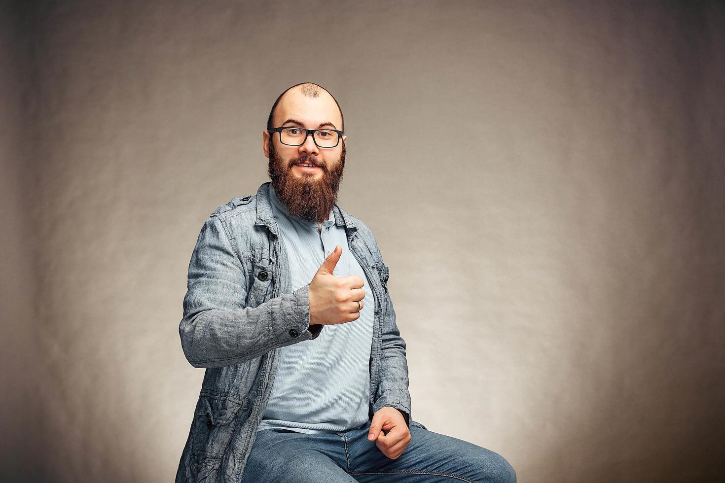 a bearded man in glasses showing thumb up, happy emotions photo