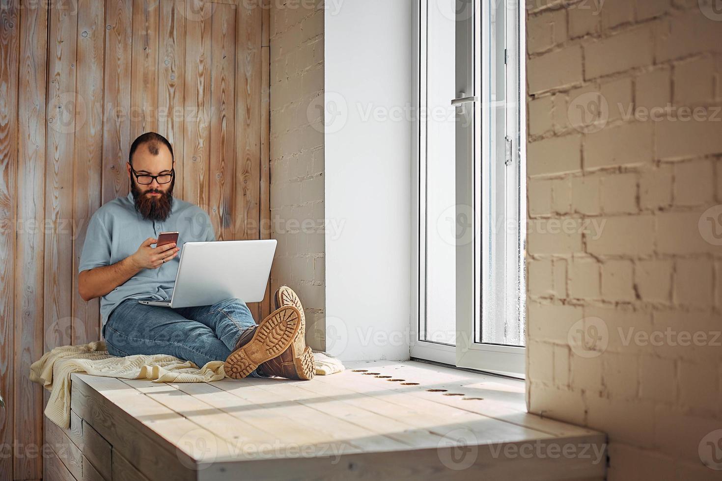 estilo de vida exitoso hombre independiente con barba logra un nuevo objetivo con una computadora portátil en el interior del loft. foto