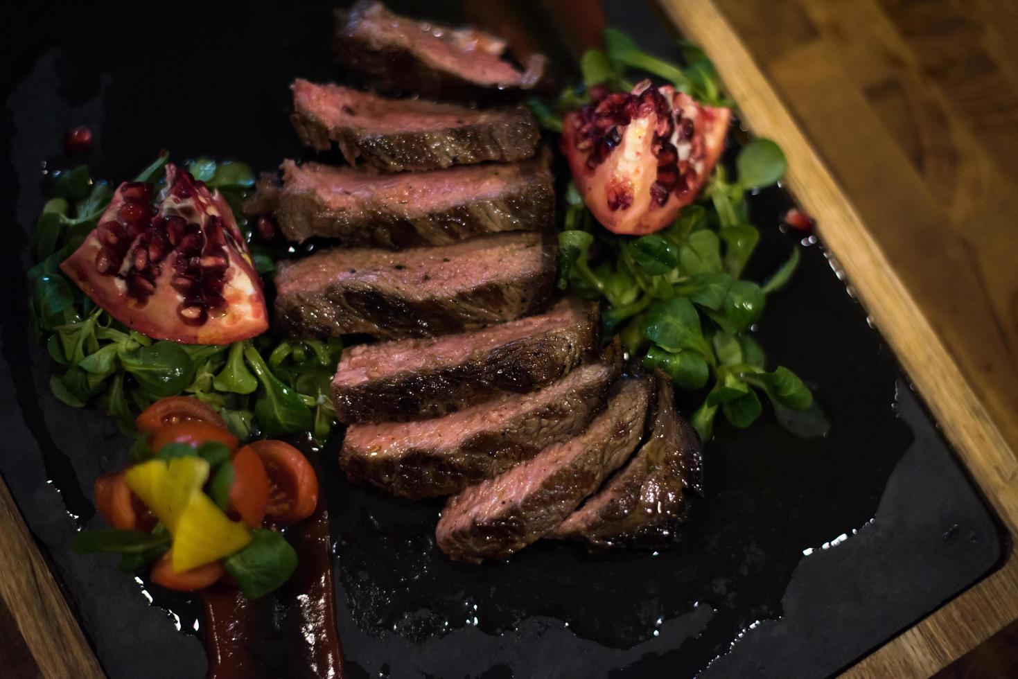 Juicy slices of grilled steak on wooden board photo