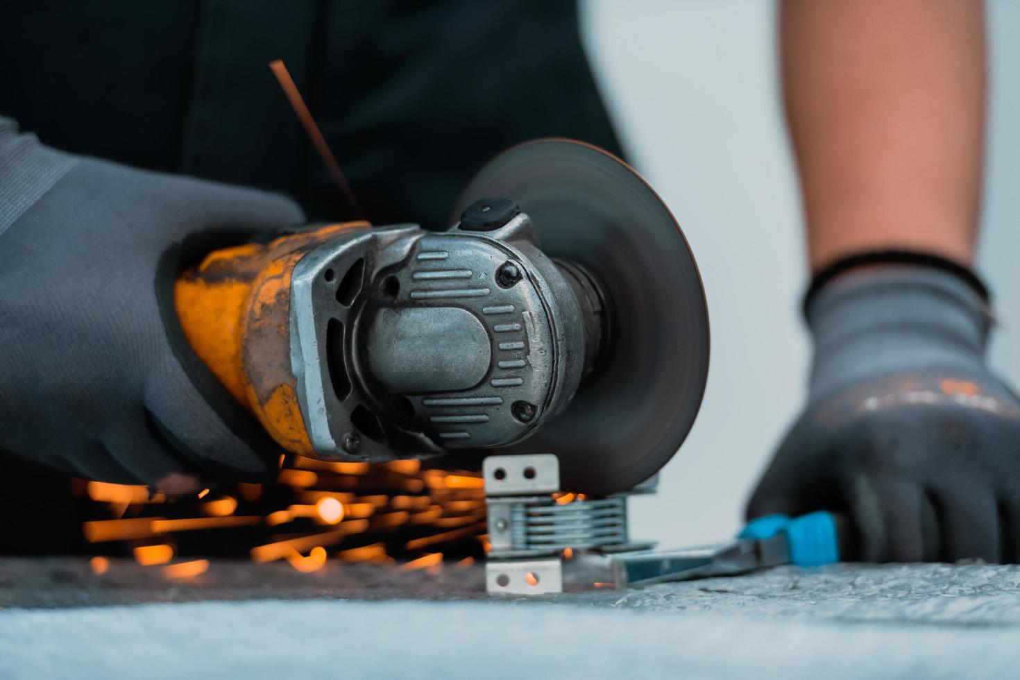 Heavy Industry Engineering Factory Interior with Industrial Worker Using Angle Grinder and Cutting a Metal Tube. Contractor in Safety Uniform and Hard Hat Manufacturing Metal Structures. photo