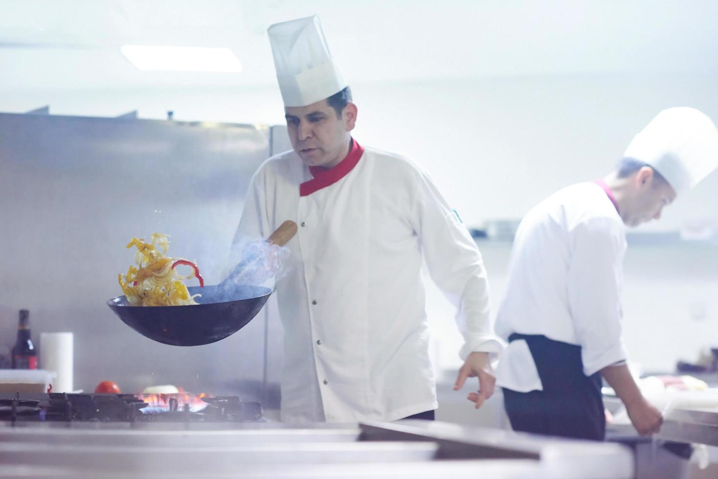 chef in hotel kitchen prepare food with fire photo