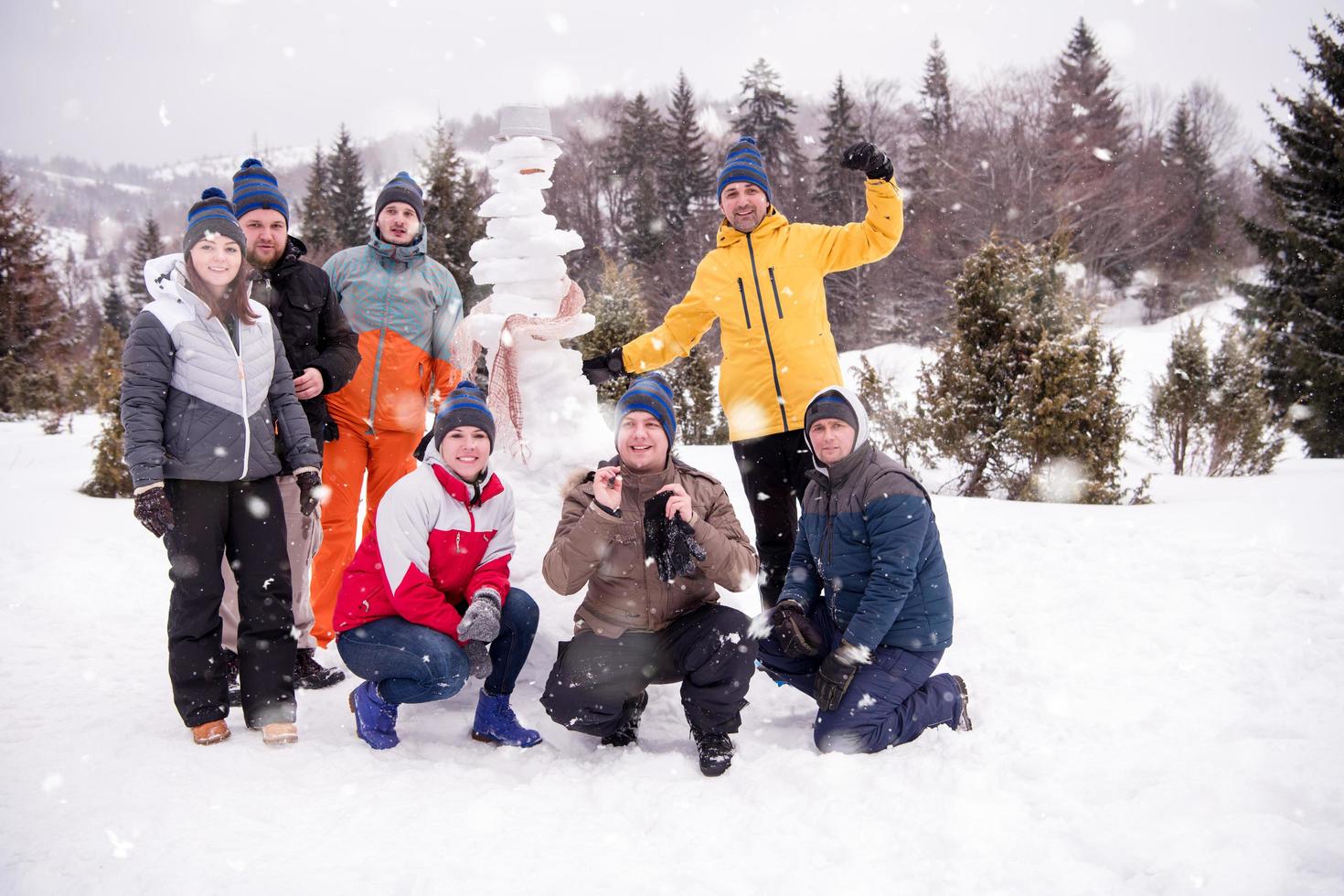 retrato de grupo de jóvenes posando con muñeco de nieve foto