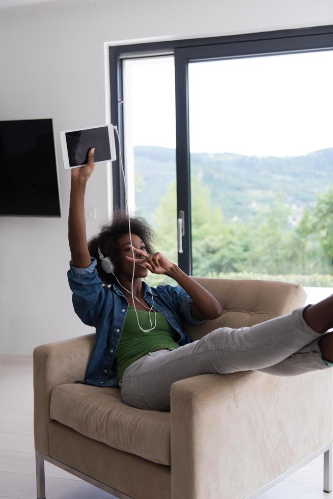 African american woman at home in chair with tablet and head phones photo