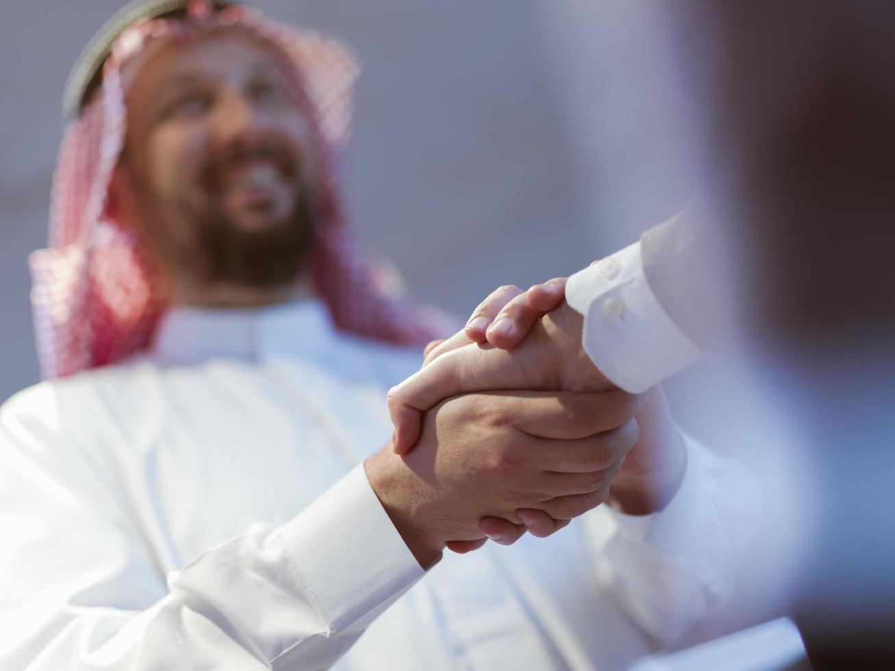 Business meeting with arab man and shaking each other hands in greetings and introduction discussing and planning within modern office in background photo