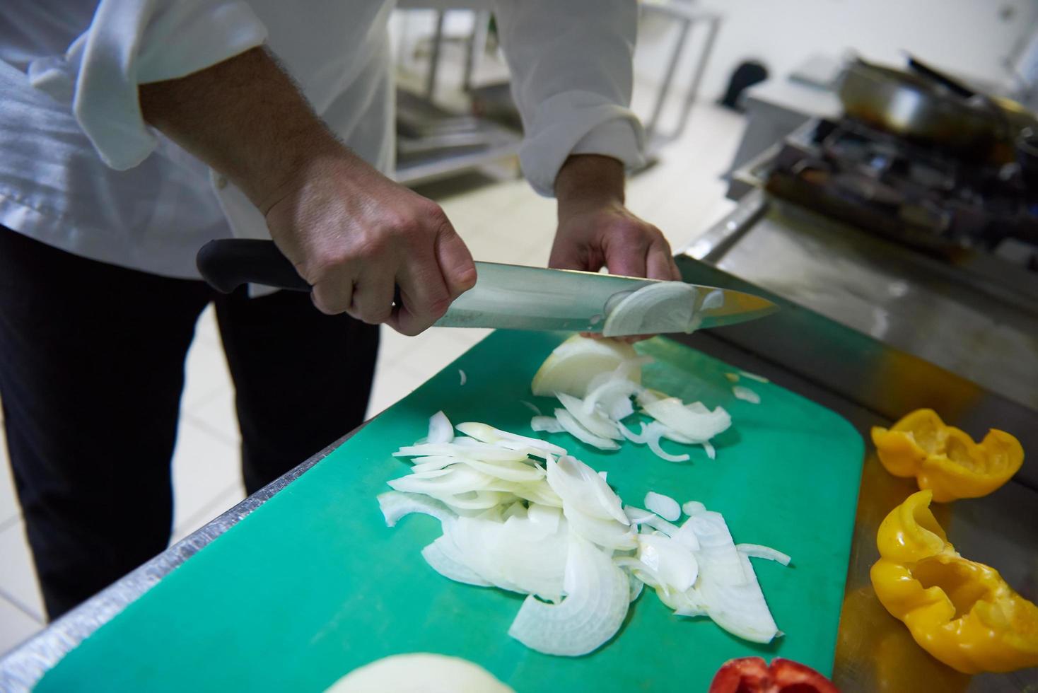 chef in hotel kitchen  slice  vegetables with knife photo