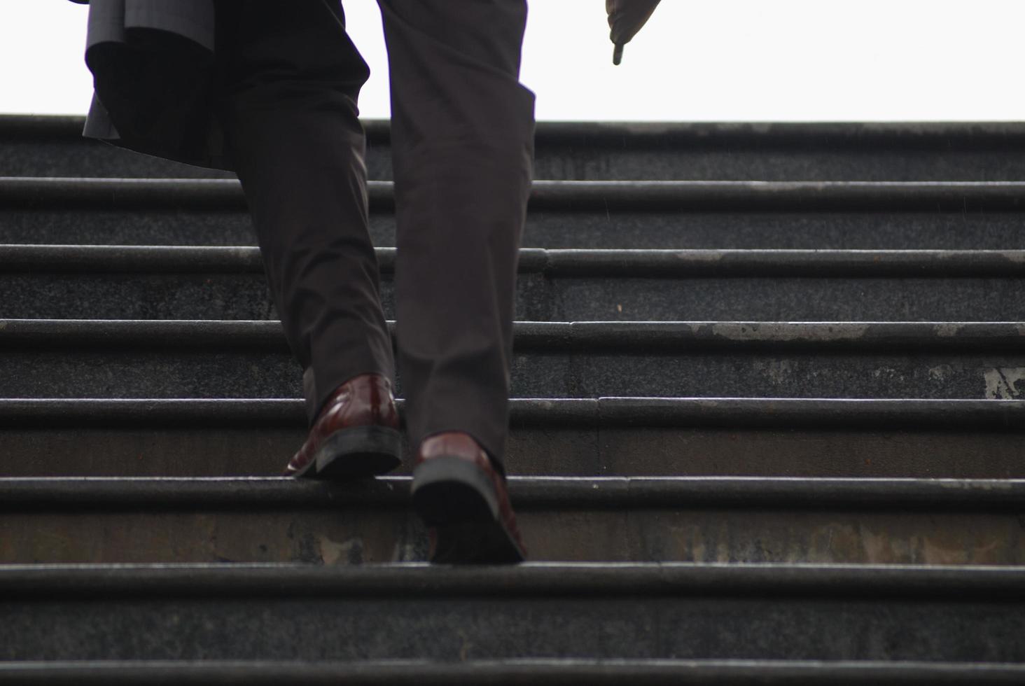 business executive climbing up stairs with umbrela in his hand photo