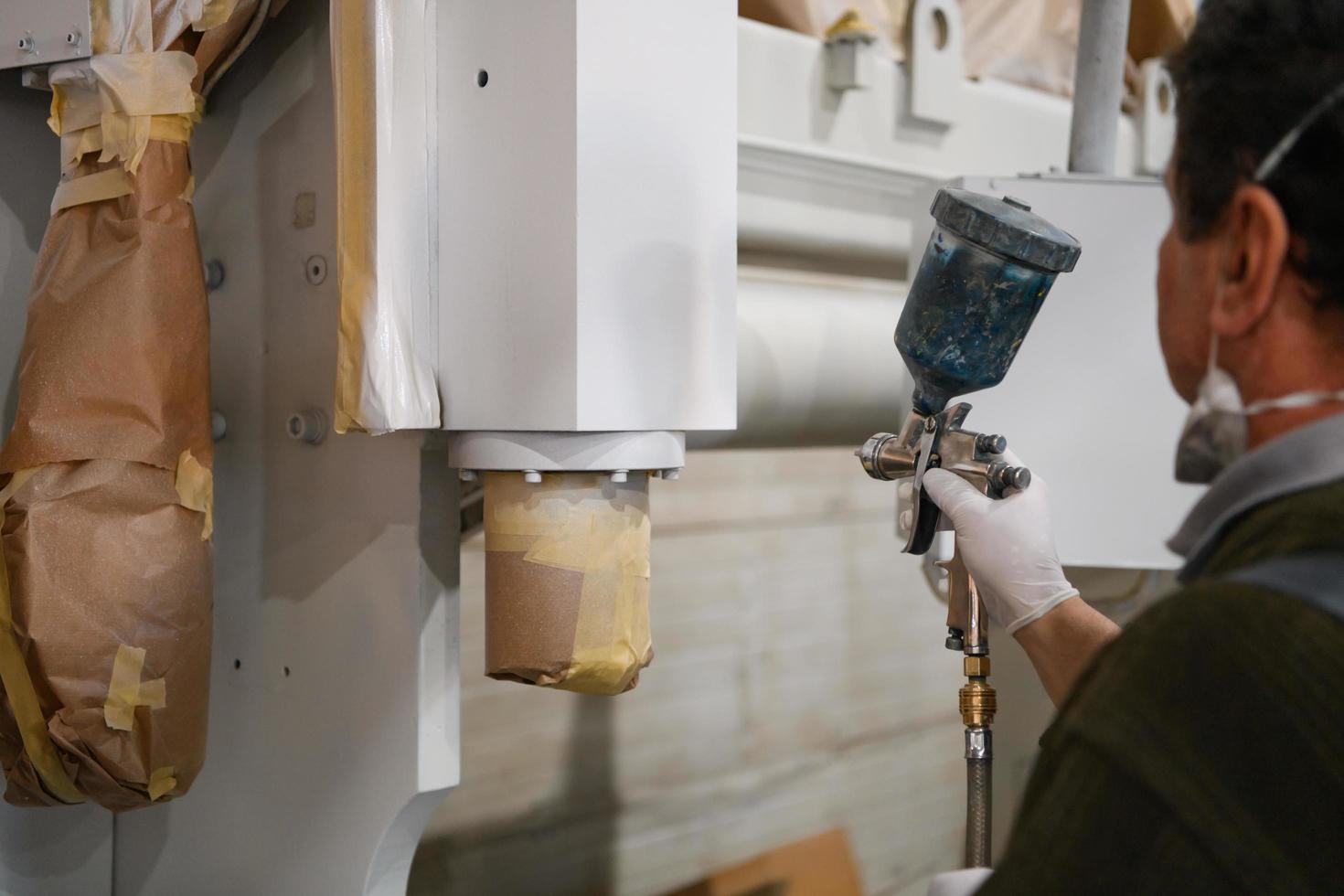 A worker painting to mechanical part with airless spray photo