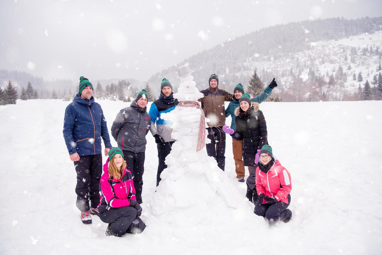 retrato de grupo de jóvenes posando con muñeco de nieve foto