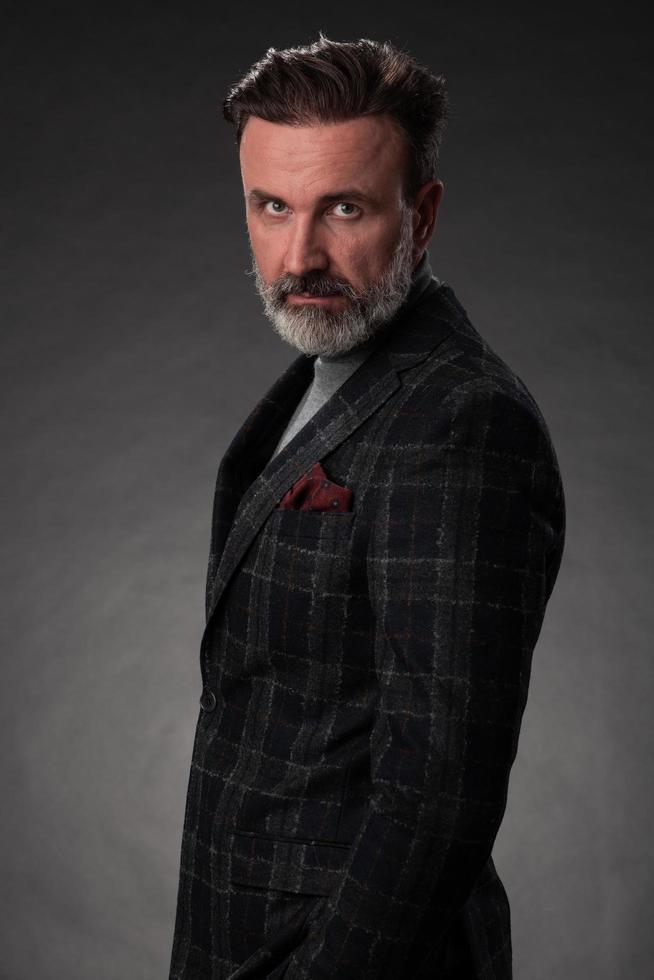 retrato de un elegante hombre de negocios de alto nivel con barba y ropa informal de negocios en un estudio fotográfico aislado en un fondo oscuro gesticulando con las manos foto