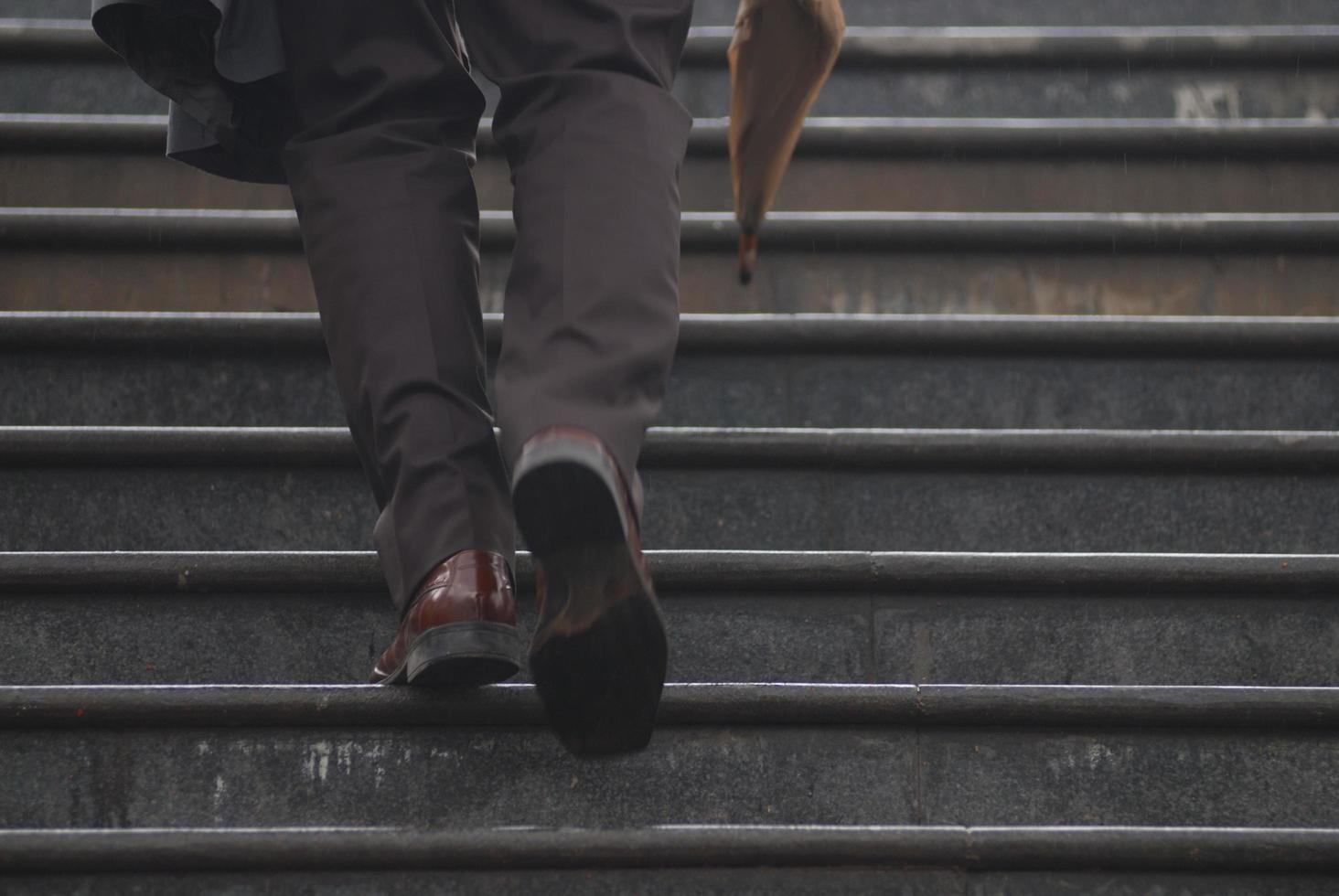 ejecutivo de negocios subiendo escaleras con paraguas en la mano foto