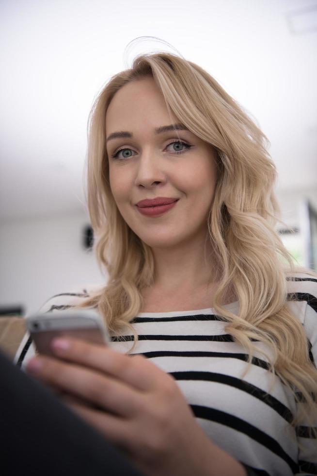woman sitting on sofa with mobile phone photo