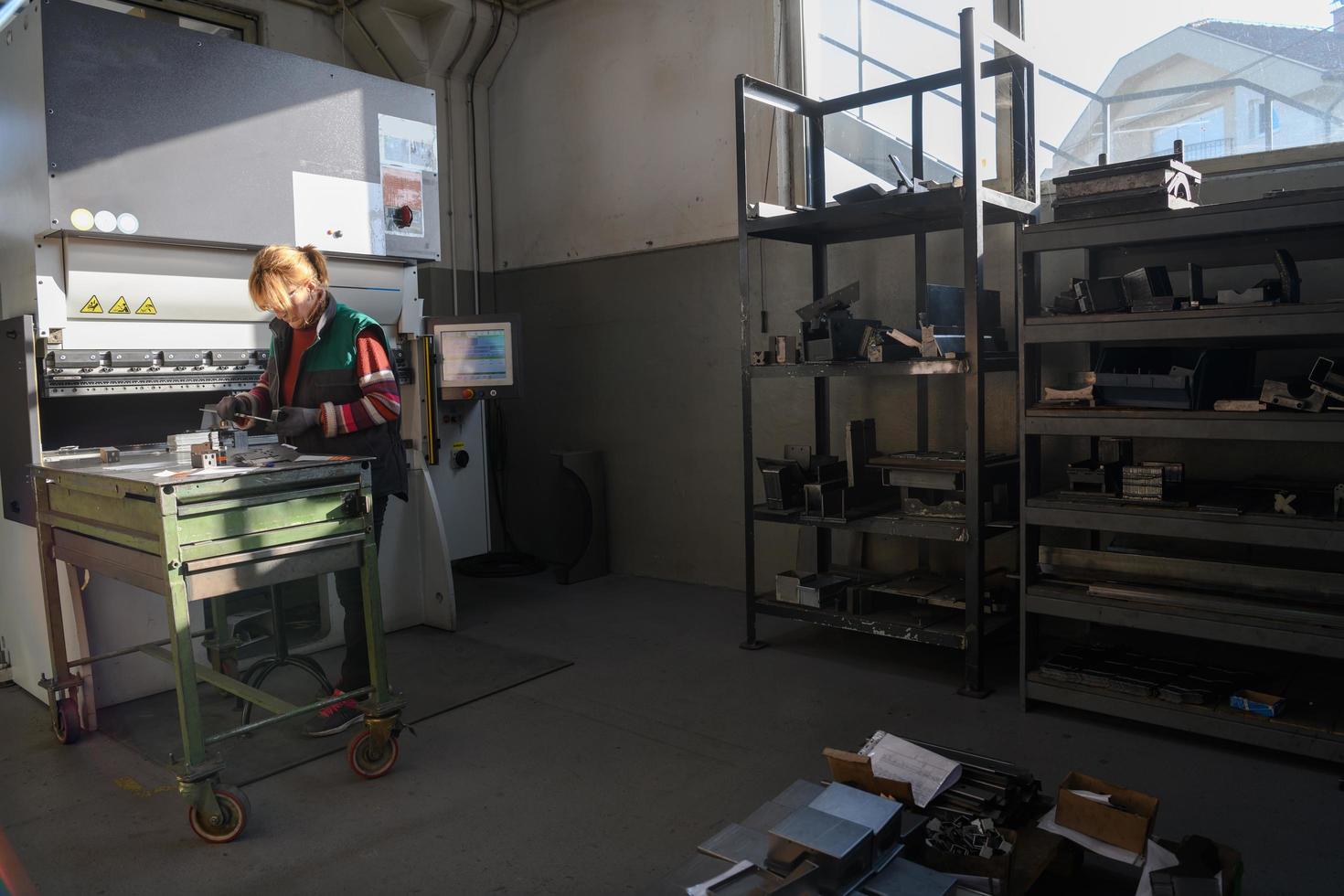 mujer que trabaja en una fábrica moderna y prepara material para una máquina cnc. foto