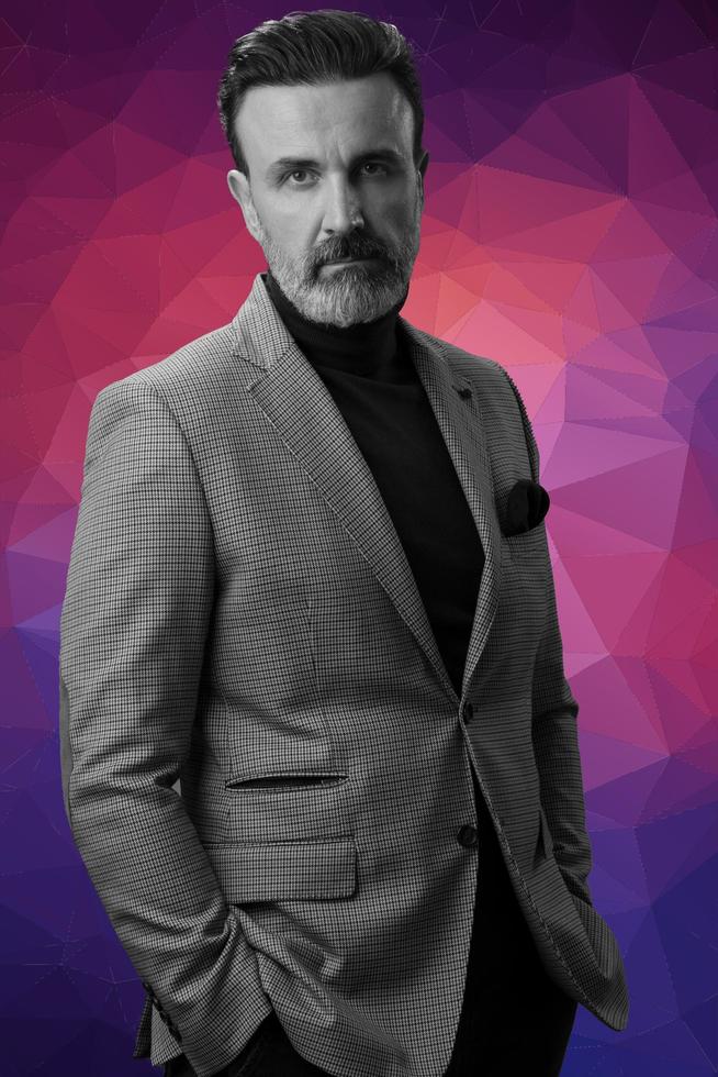 Black and white portrait of a stylish elegant senior businessman with a beard and casual business clothes against retro colorful pattern design background gesturing with hands photo