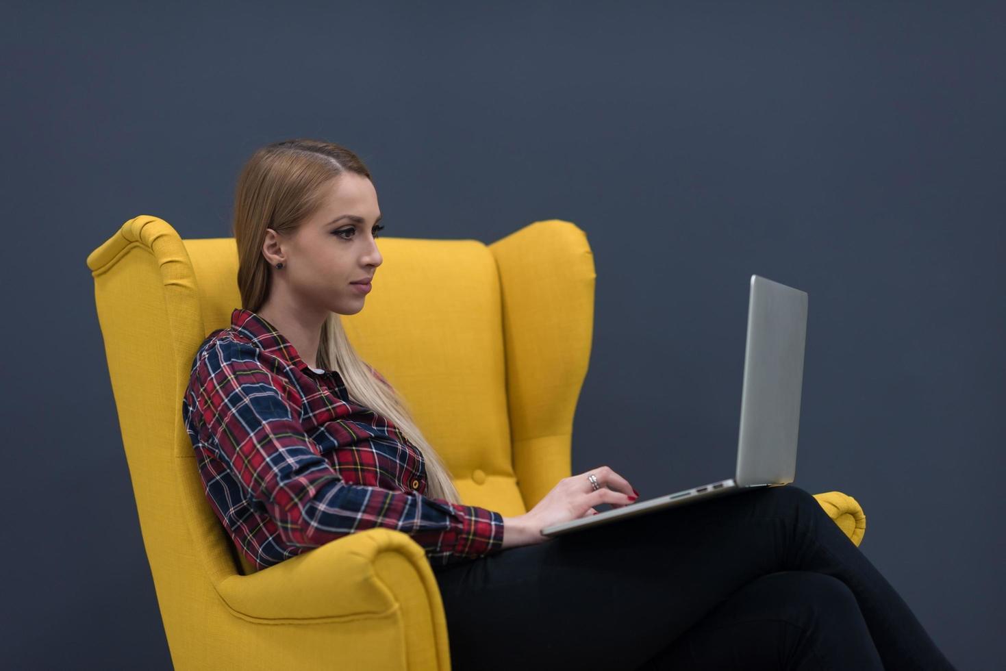 startup business, woman  working on laptop and sitting on yellow armchair photo