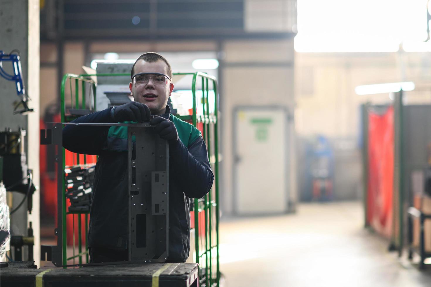 a uniformed worker working in a modern metal production and processing factory assembles parts of a new machine on his desk photo