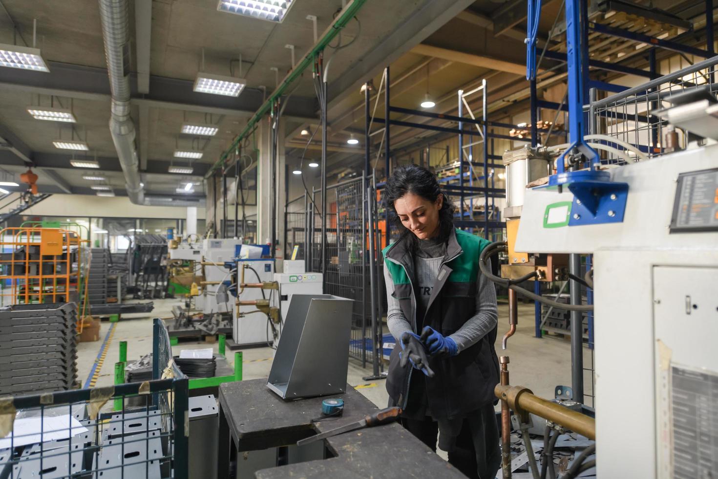 turquía, 2022 - una mujer que trabaja en una moderna fábrica de metal ensambla piezas para una nueva máquina foto