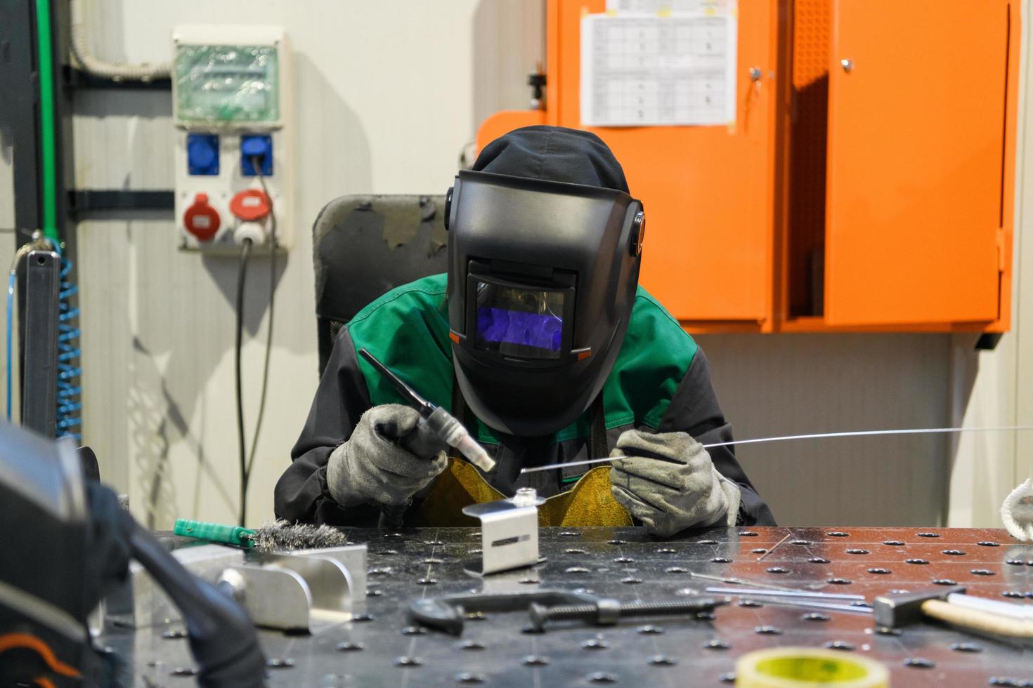 A woman employed in a modern factory for the production and processing of metals in a work uniform welds metal materials photo