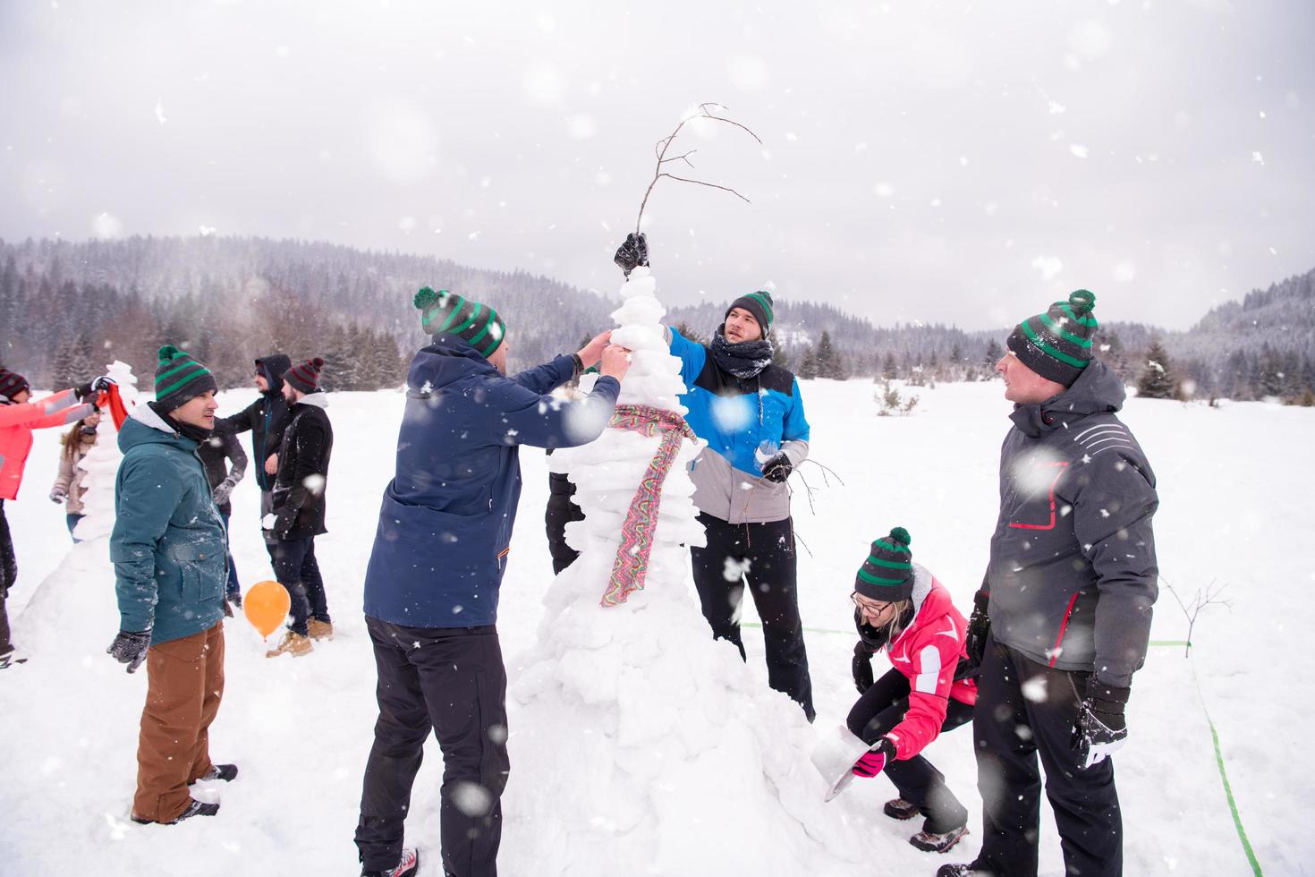 group of young people making a snowman photo