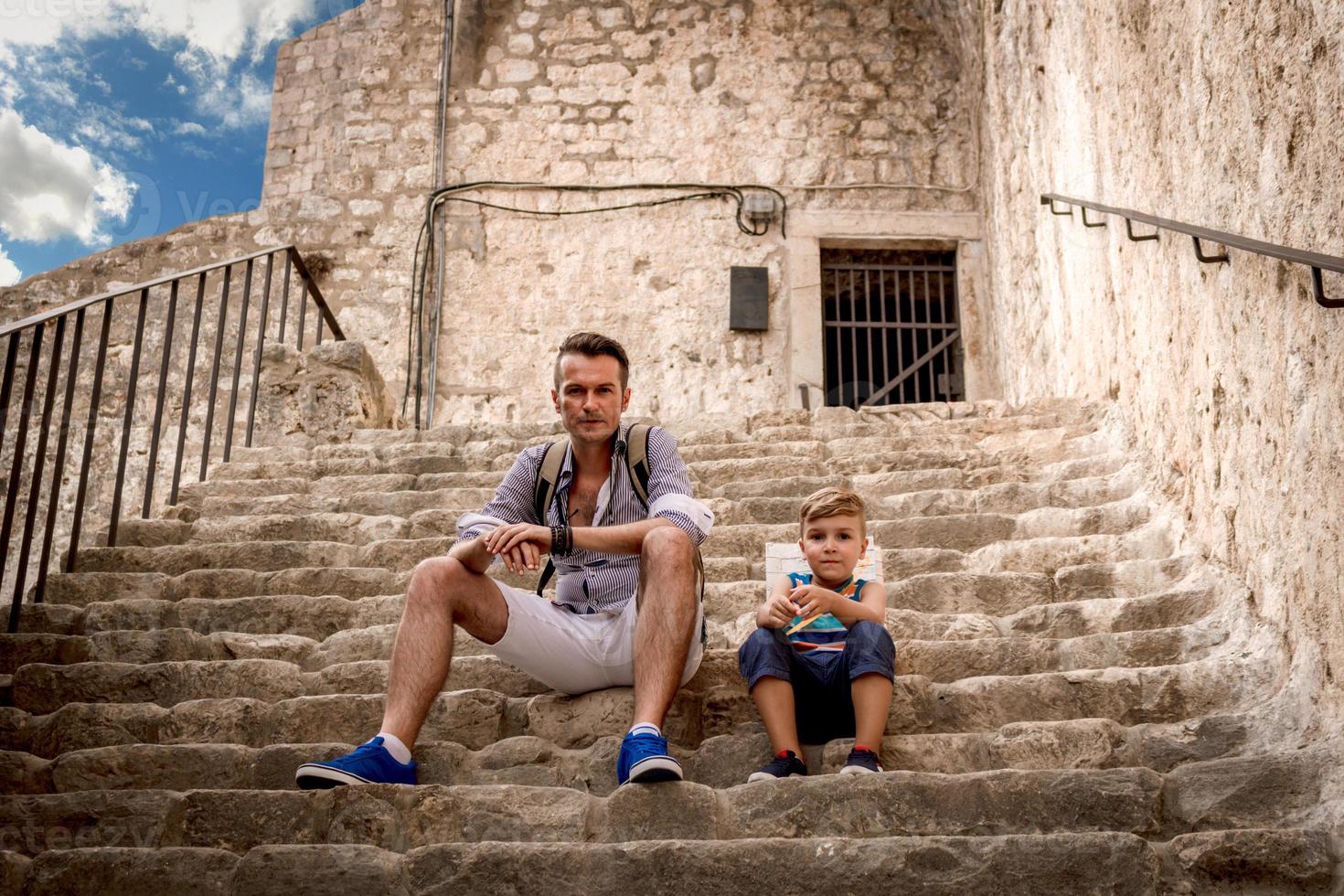 Father and son resting cobblestone staircase. photo