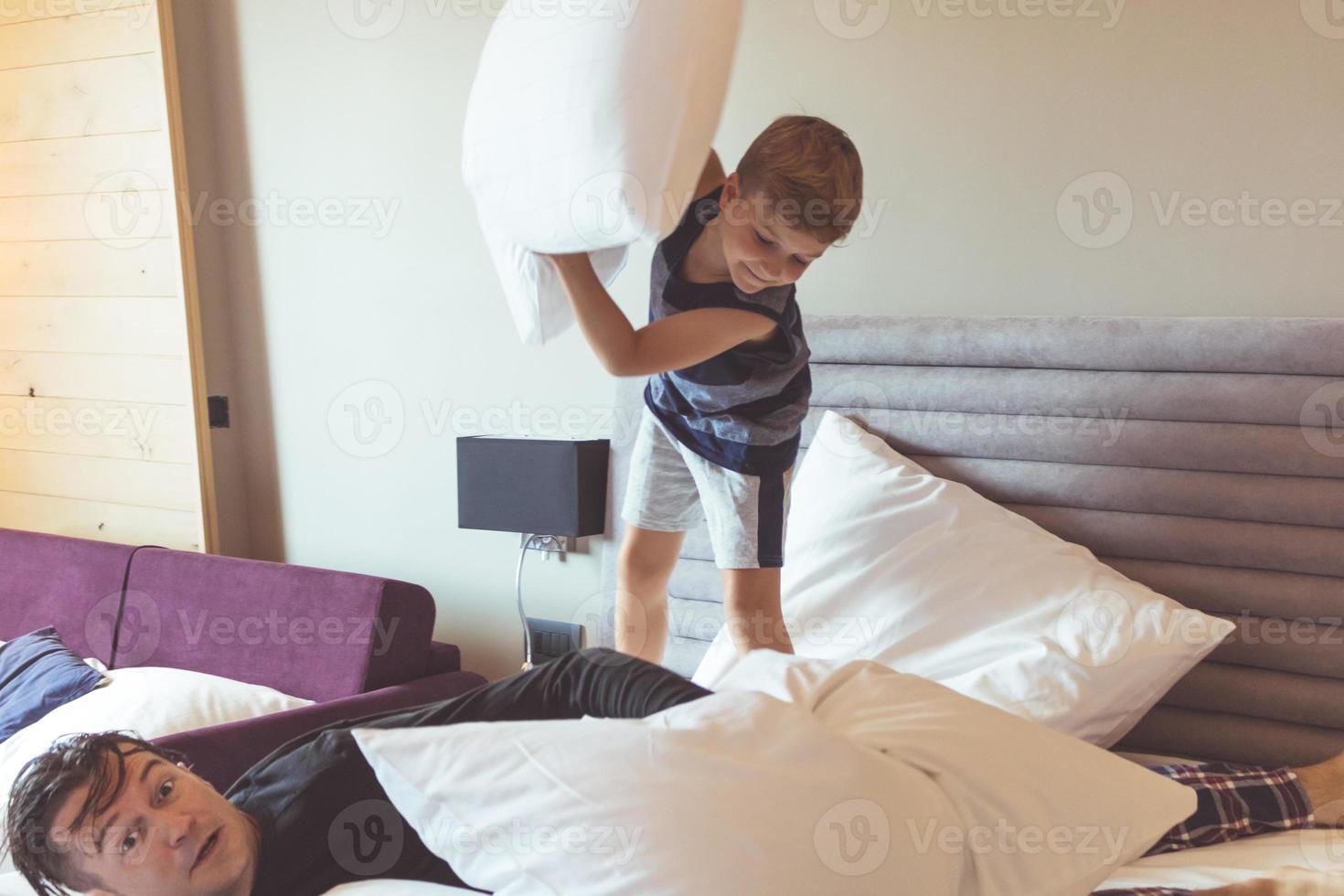 Small boy having fun while pillow fighting with his father. photo